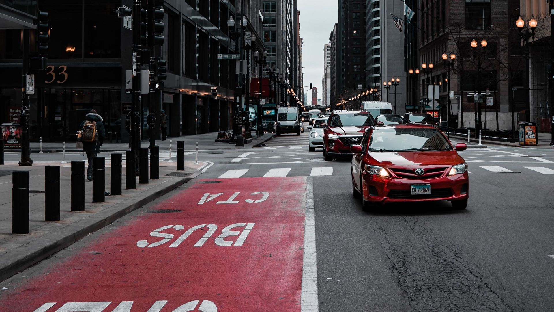 View of a bustling city street with cars, buildings, and designated bus lane.