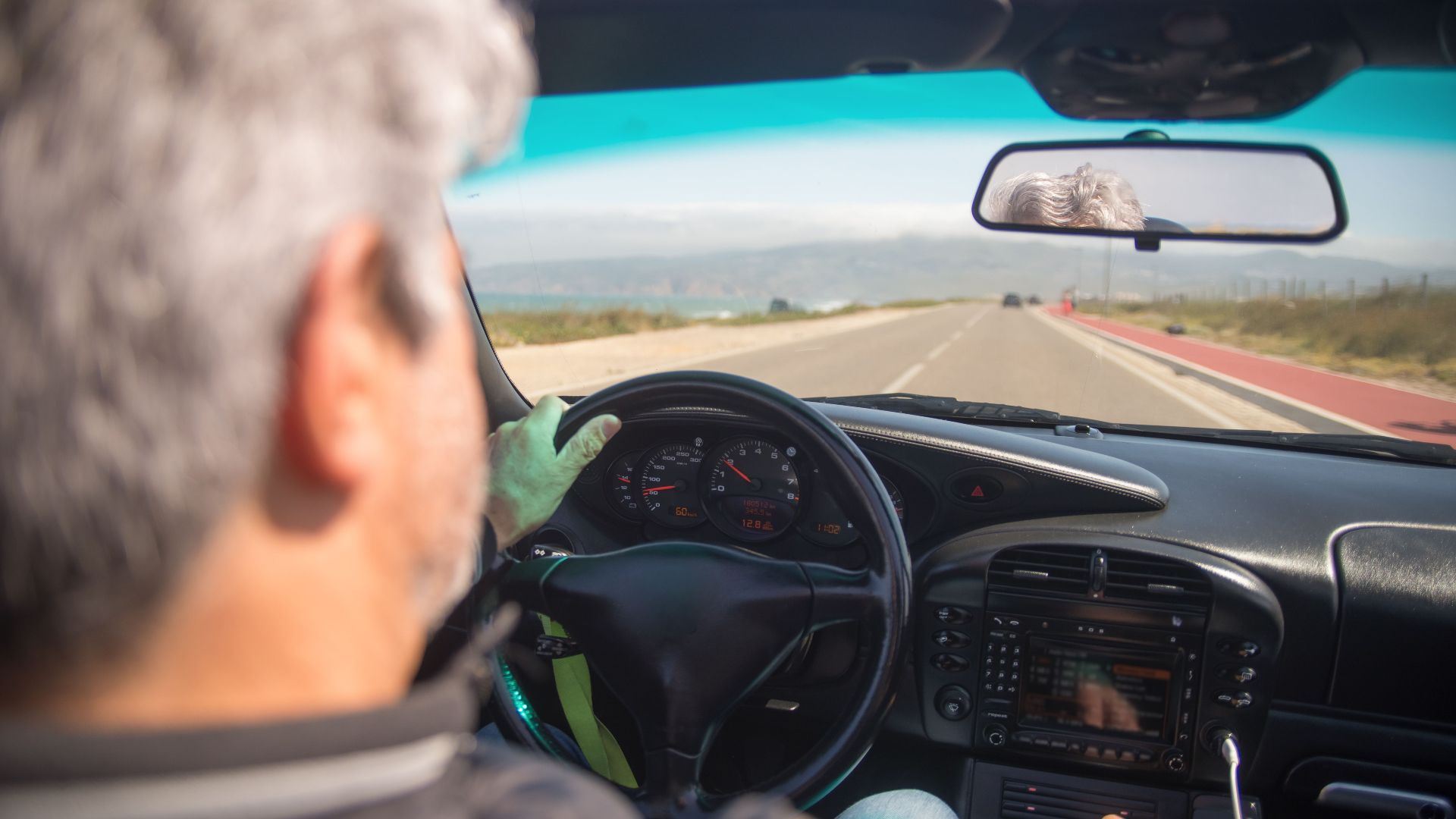 A person driving a car on a scenic highway in Portugal on a sunny day.