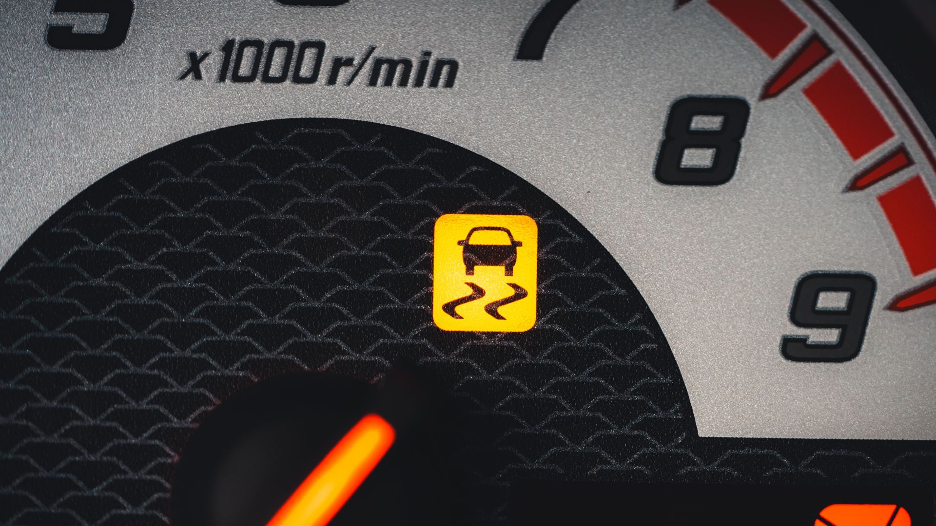 Close-up of a car dashboard showing a yellow traction control warning light.