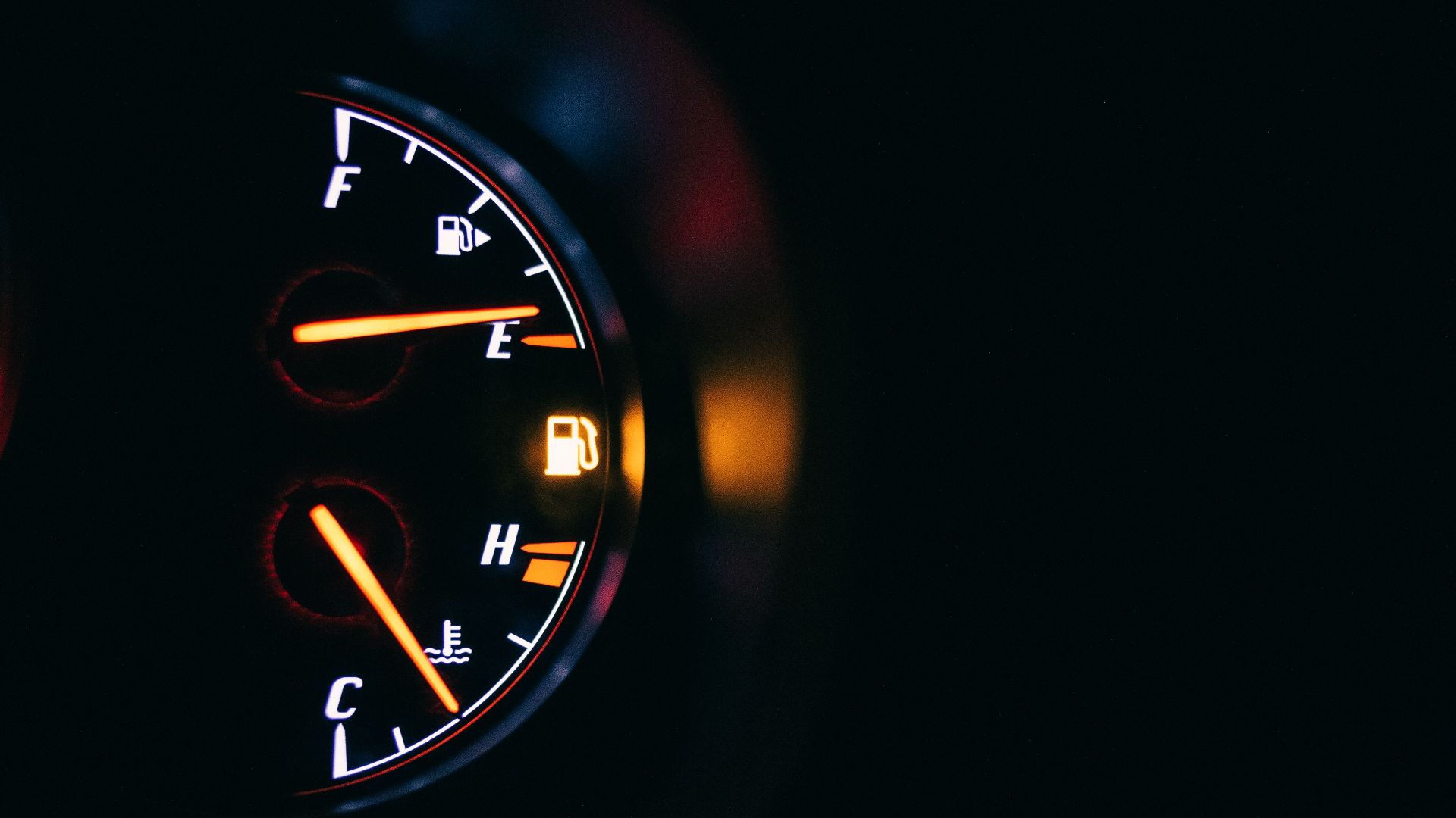 Automobile dashboard with fuel gauge representing scale and gas station symbols between letters in auto on black background