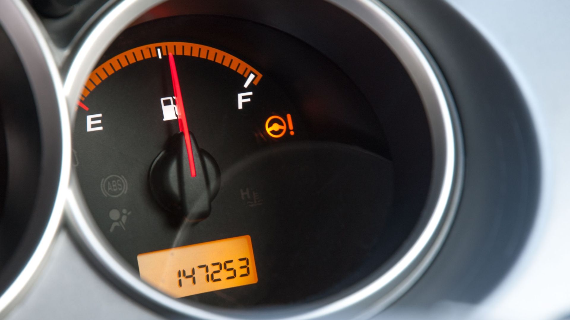 Detailed close-up of a car's fuel gauge with odometer showing a reading of 147253 miles.