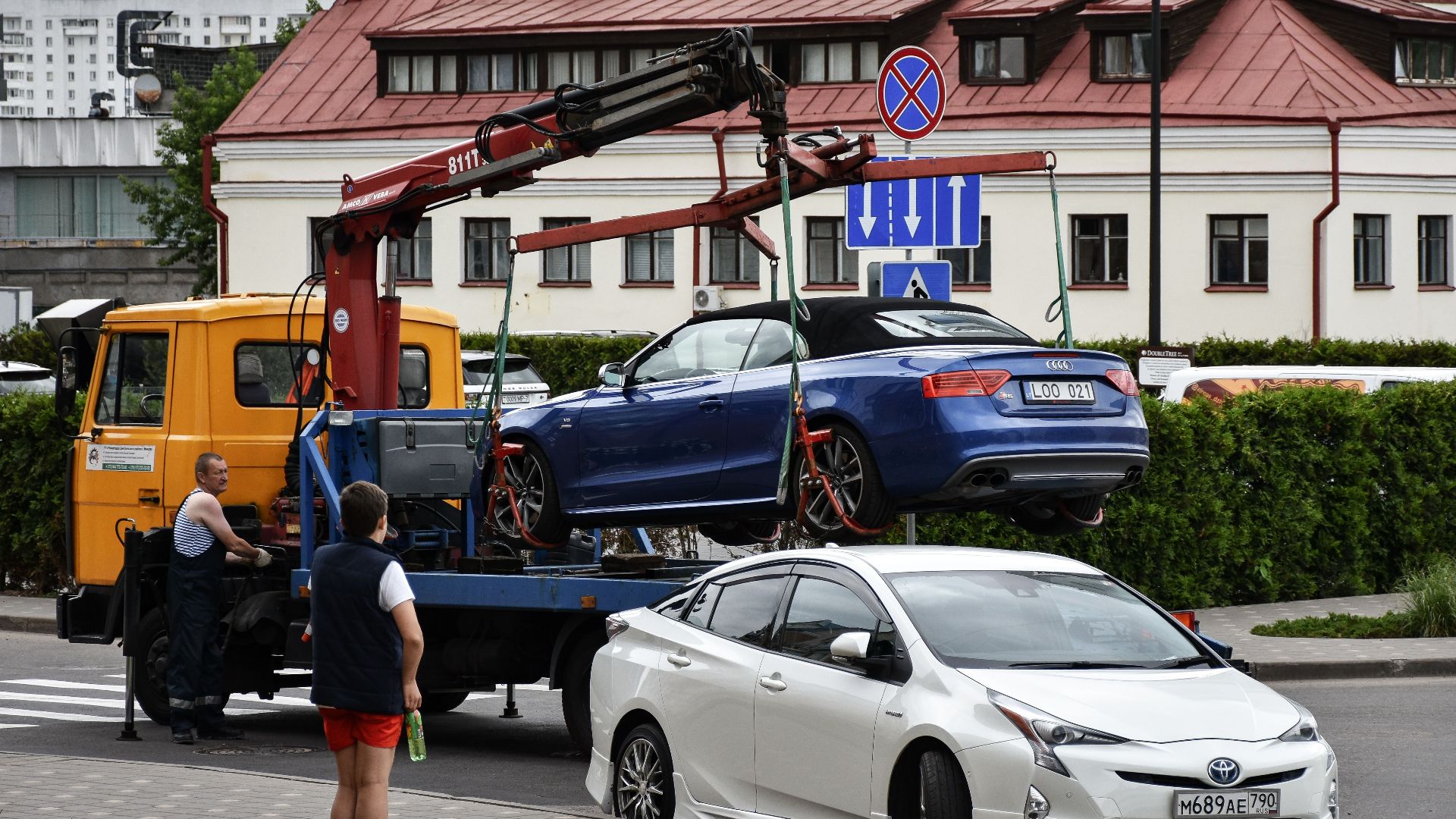 Towing a blue Audi convertible in a bustling city street.