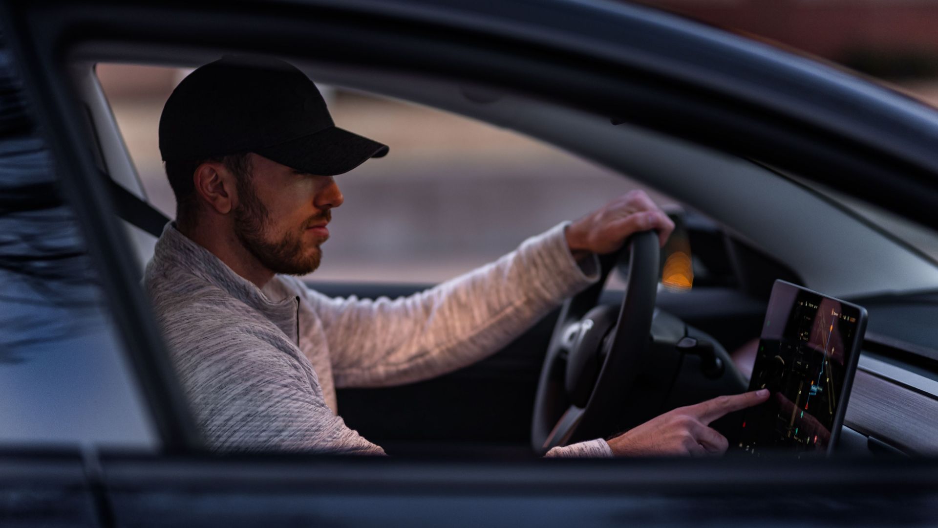 A man interacts with a touchscreen inside an electric car, driving through Dallas, TX.