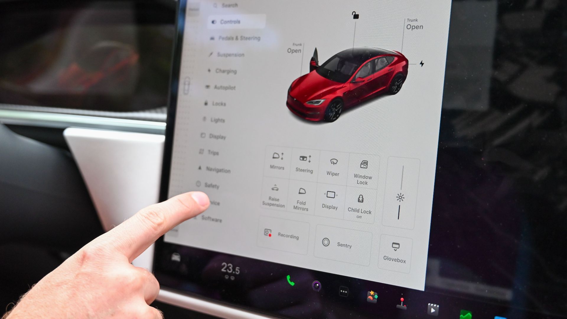 Close-up of a hand interacting with a modern car's touchscreen interface for various controls.