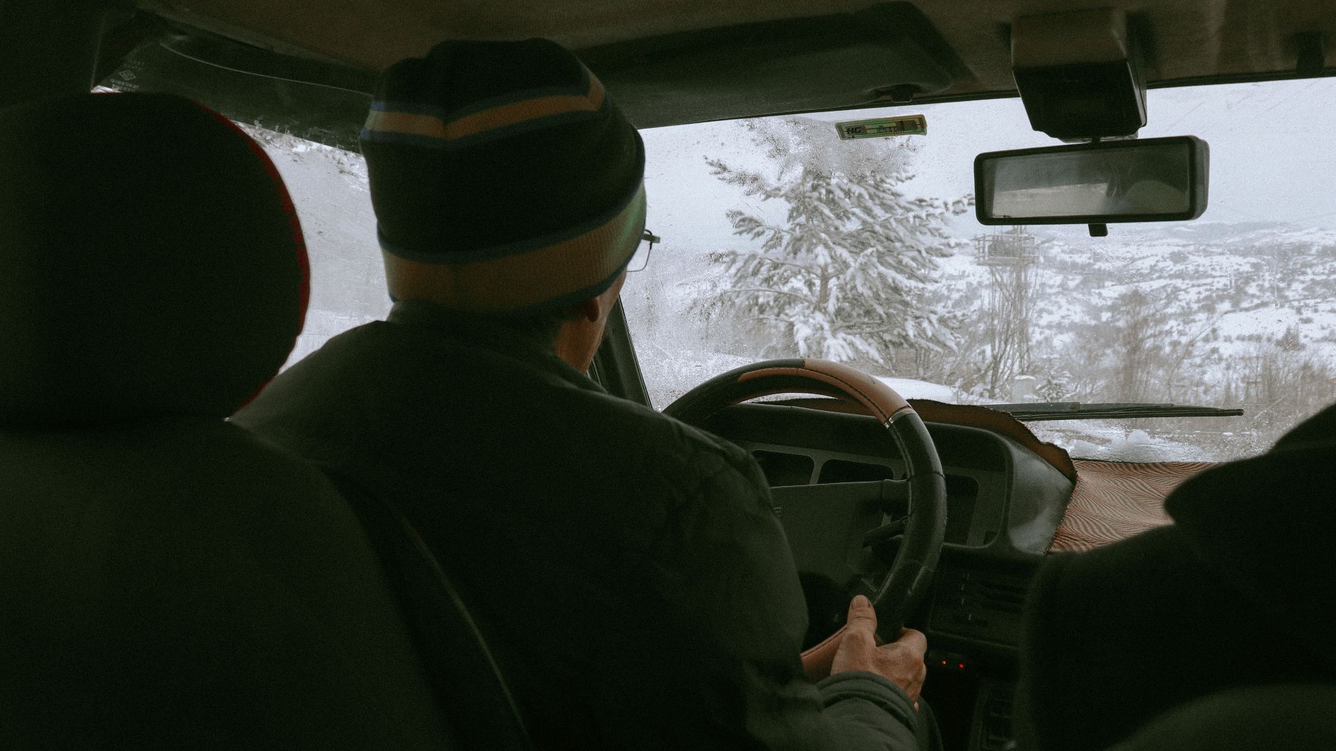 Driver navigating snowy winter landscape from vehicle's interior view.