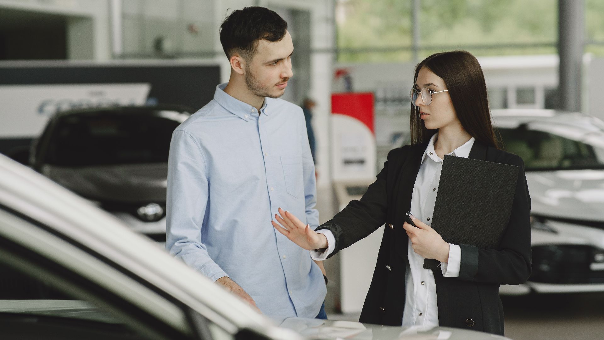 A salesperson and customer discussing car features in a dealership setting.