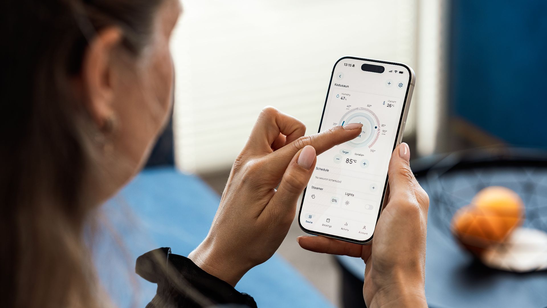 Close-up of a woman using a smartphone app to control sauna settings, indoors.