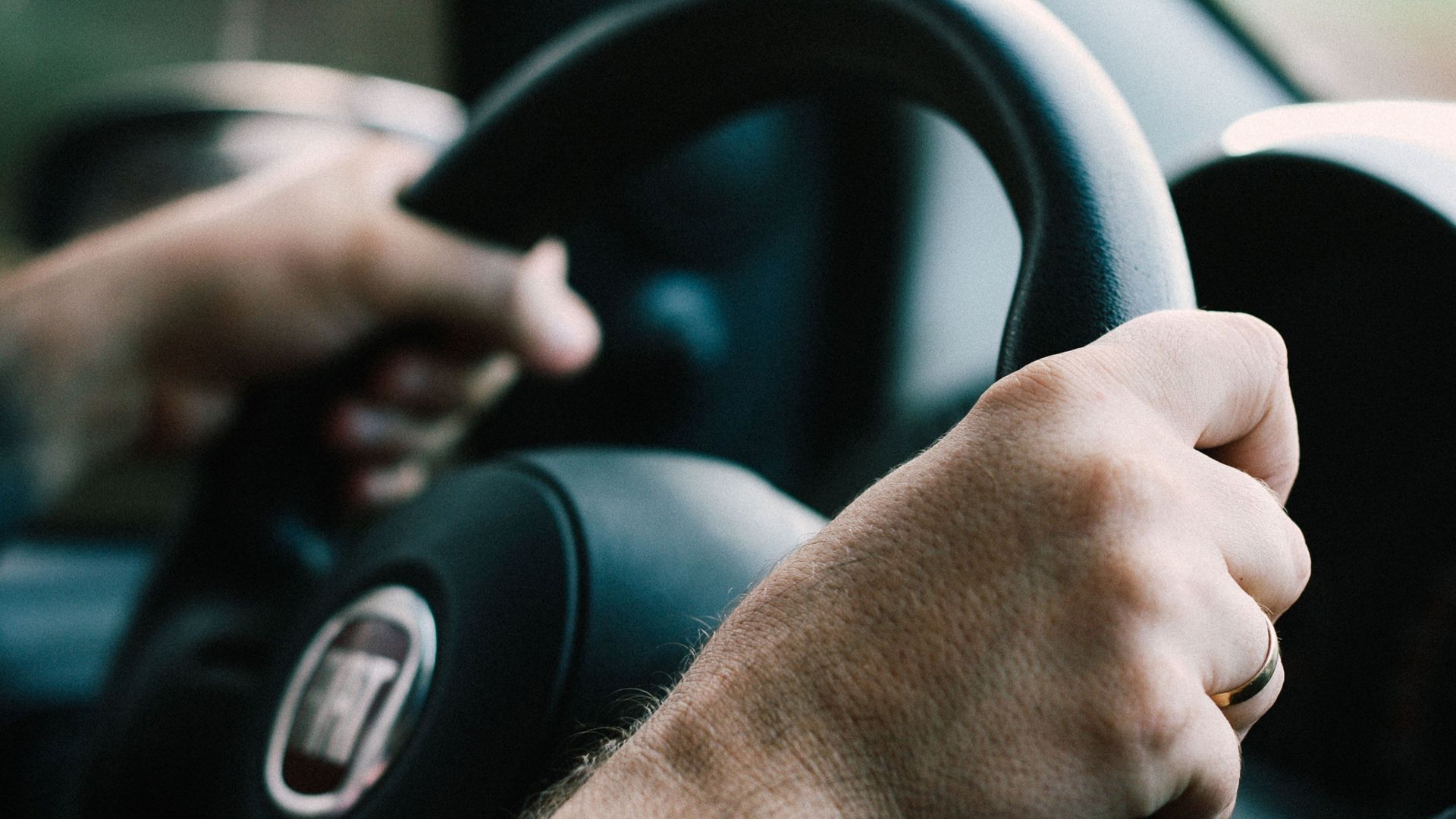 Hands firmly gripping a car steering wheel, ready to drive.