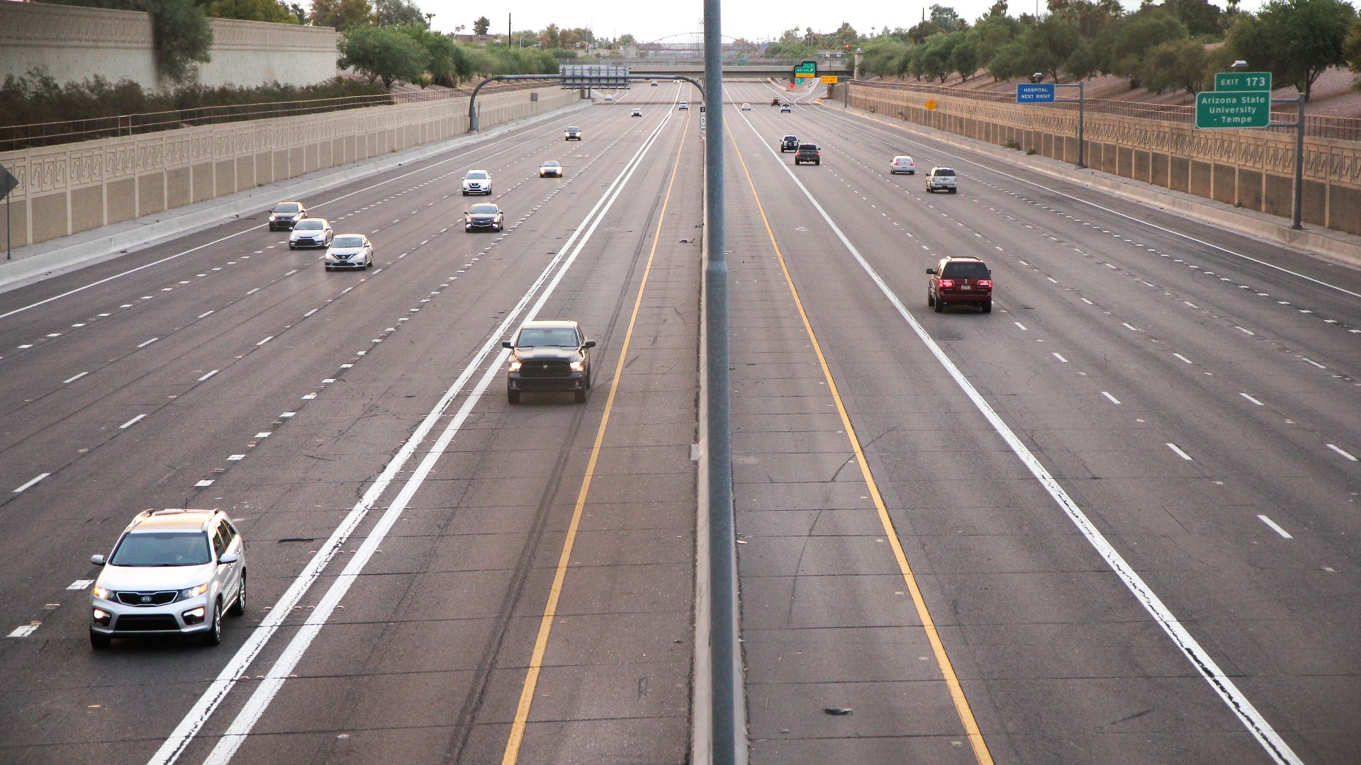 Aerial view of a deserted highway with few cars during dusk, depicting calm traffic conditions.