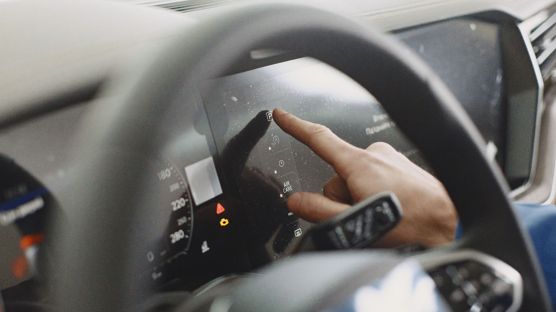 Close-up of a hand interacting with a car's digital dashboard. Modern technology and driving interface.