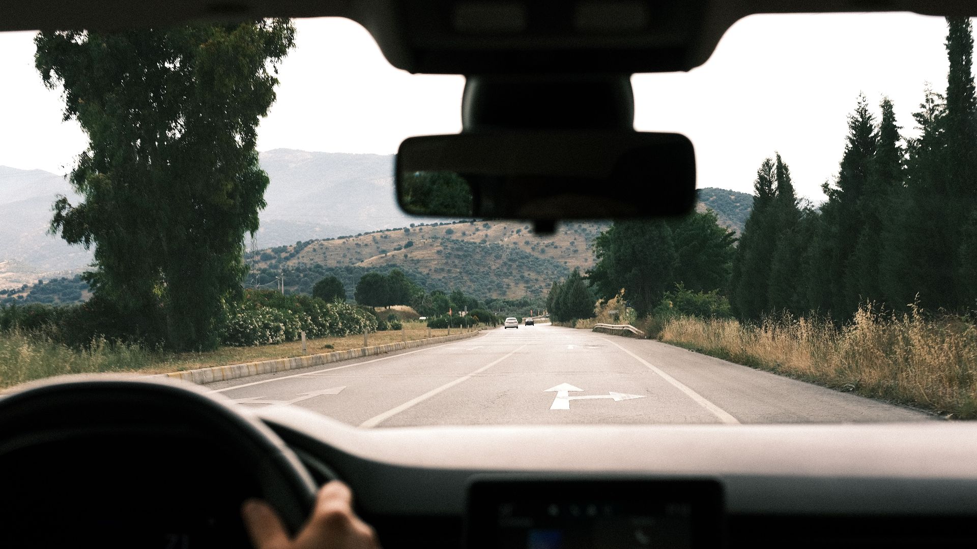 View from inside a car driving on a scenic, mountainous road during daytime.