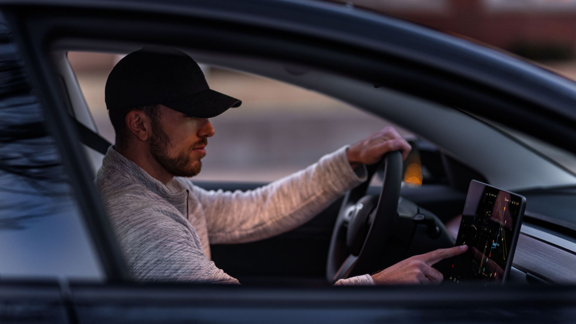 A man interacts with a touchscreen inside an electric car, driving through Dallas, TX.