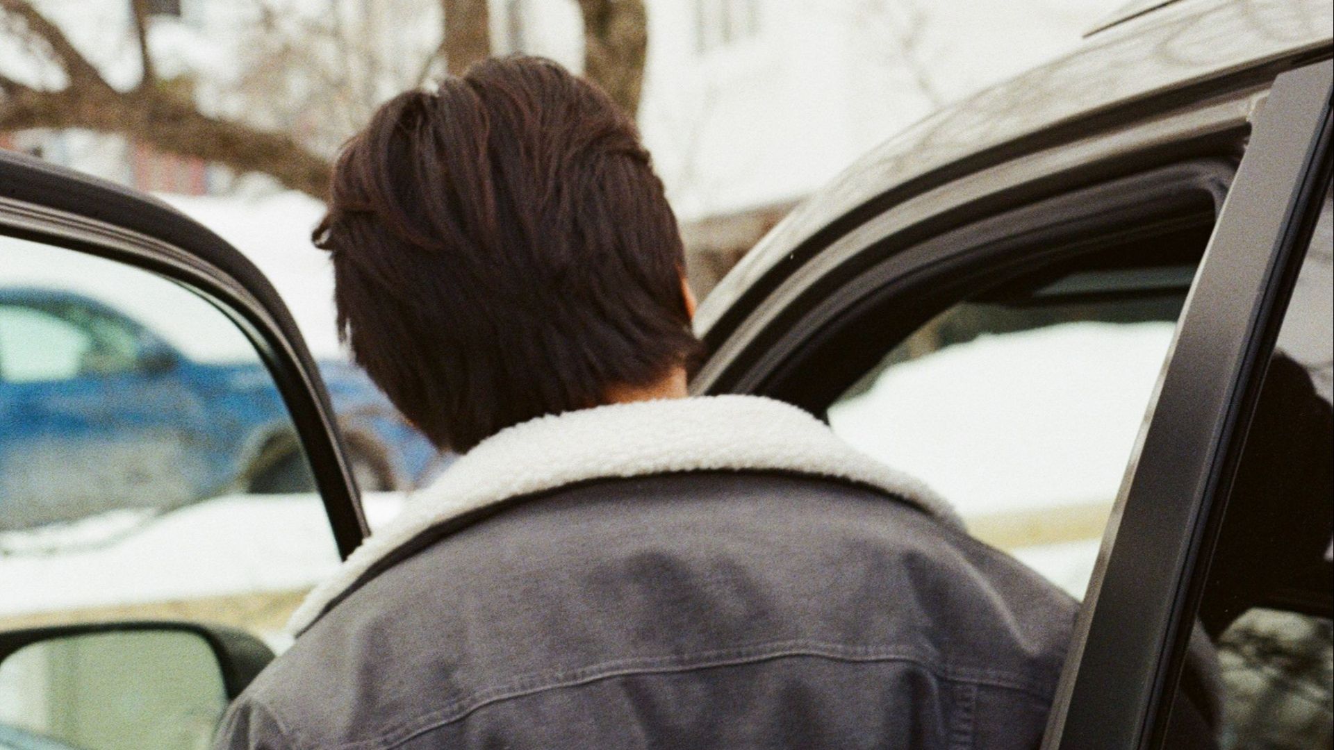 Person entering a car on a snowy winter day in Bethel, Maine, with trees in the background.