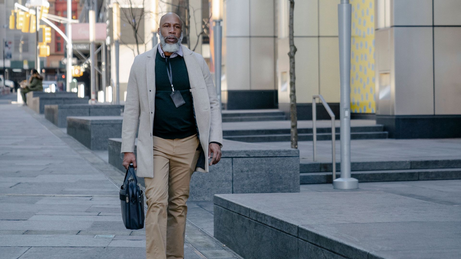 African American man walking in city street with buildings in background.
