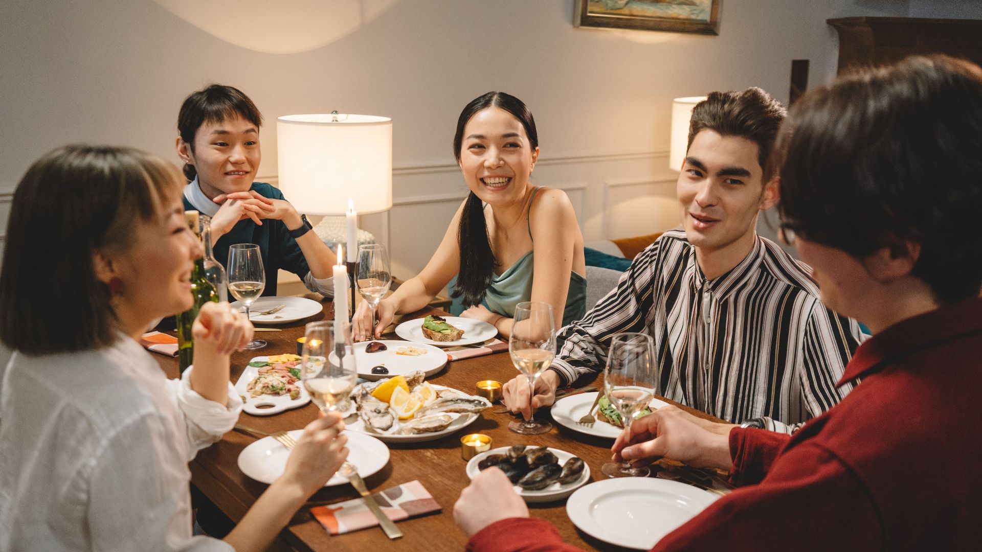 Group of friends smiling and dining together, creating a warm and cheerful indoor atmosphere.