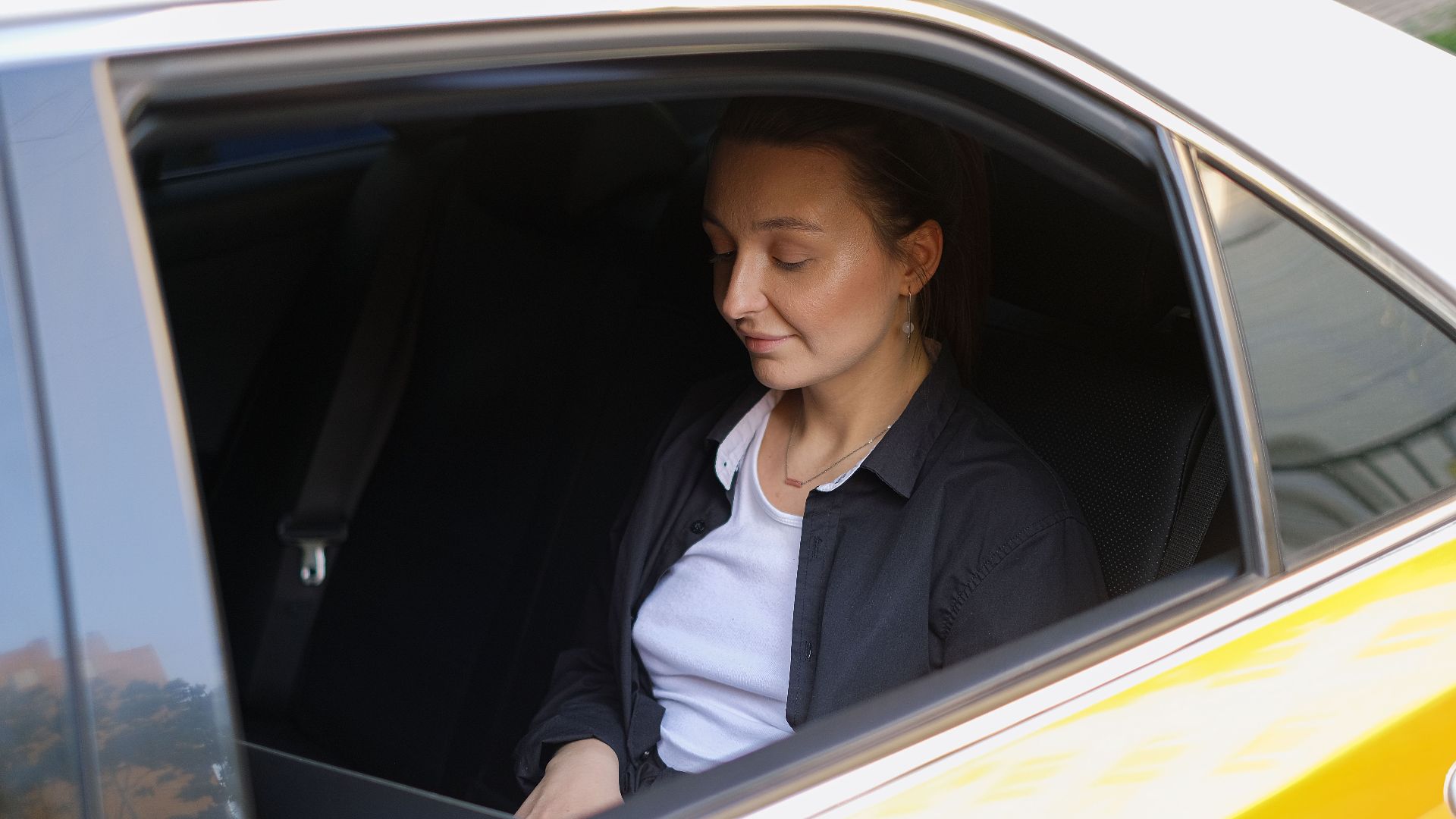 Young woman using laptop in a car, exemplifying a digital nomad lifestyle.