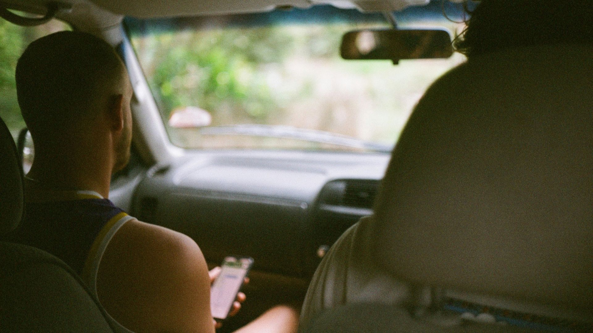 a man driving a car while holding a cell phone