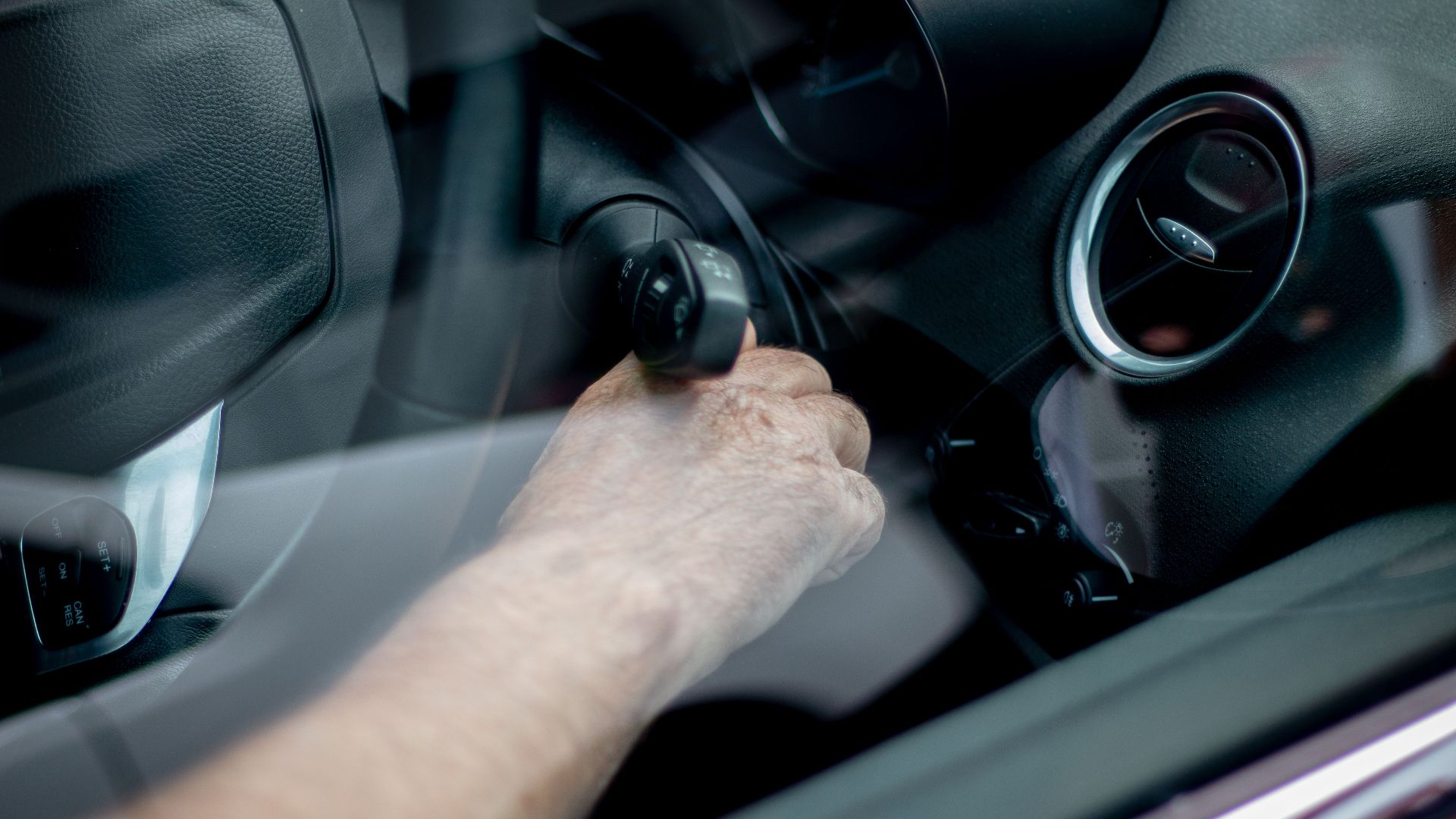 Close-up of a driver's hand starting the car ignition in Leeds, UK.