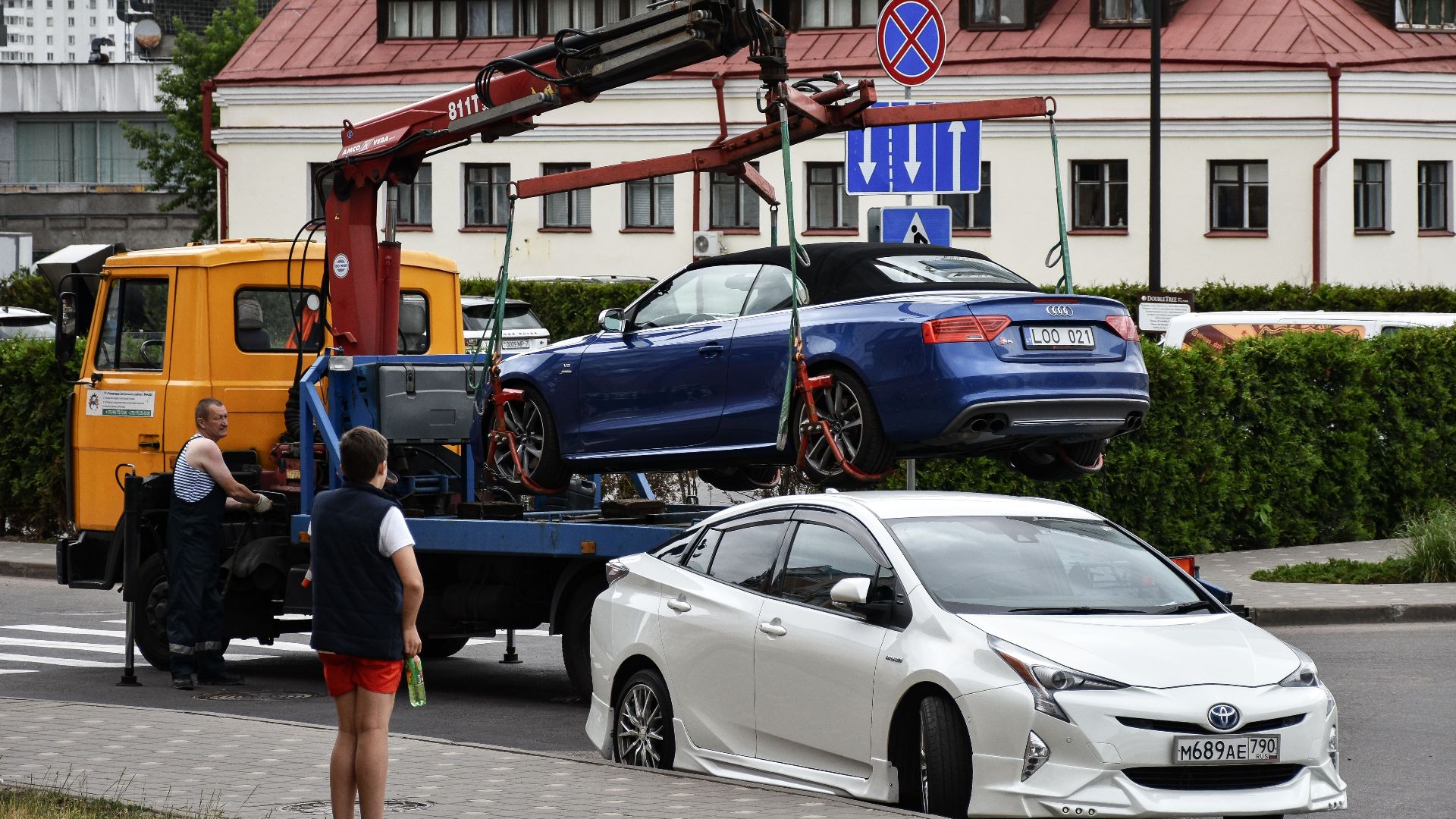 Towing a blue Audi convertible in a bustling city street.
