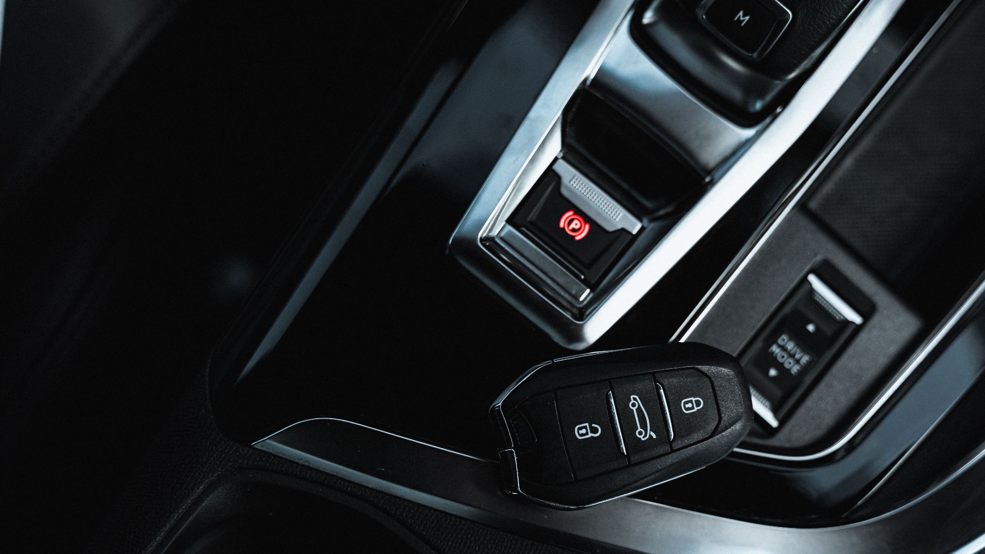 Close-up view of a keyless fob and electronic handbrake in a modern car interior.