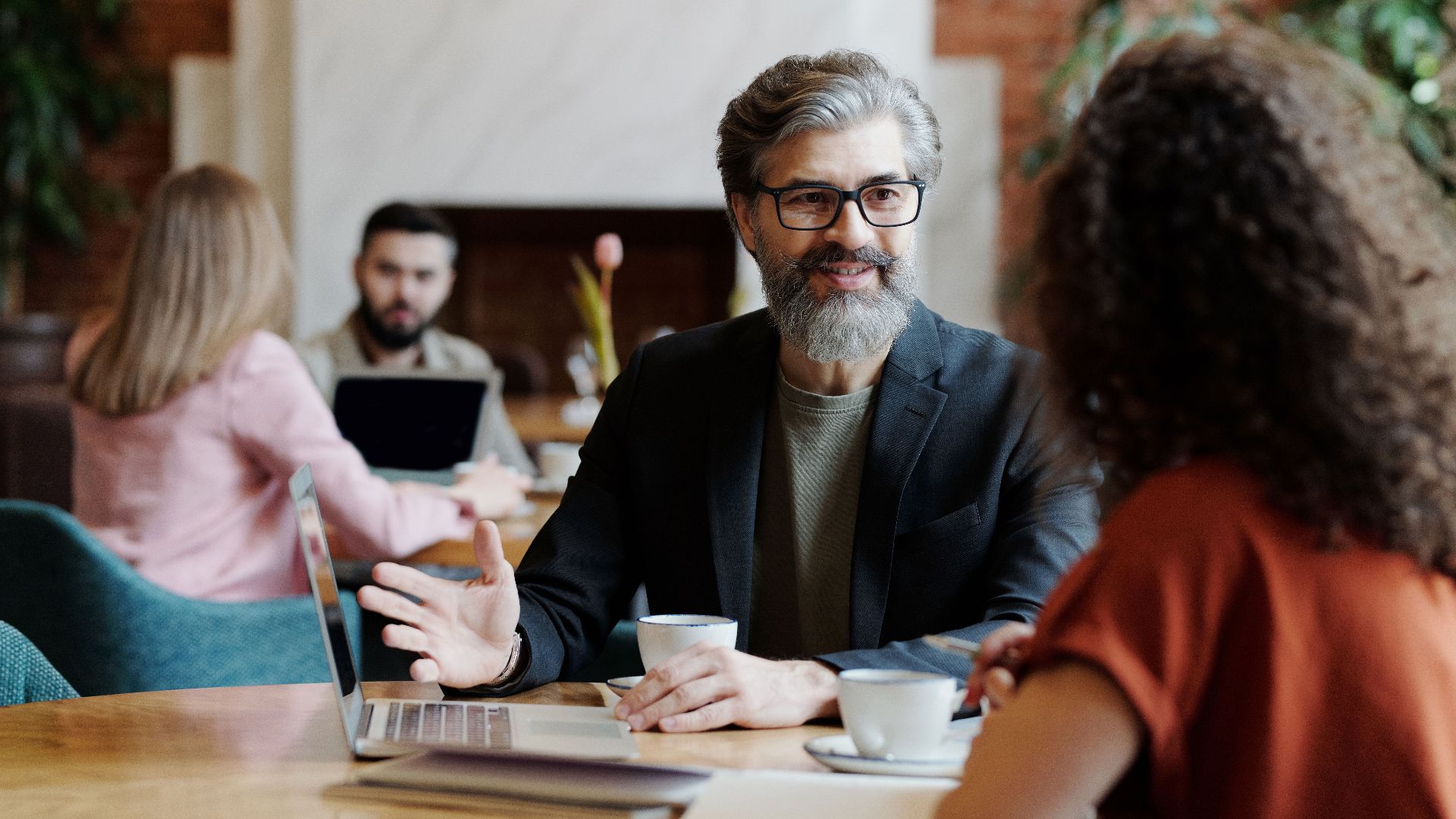Business professionals having a discussion over coffee in a modern cafe setting.