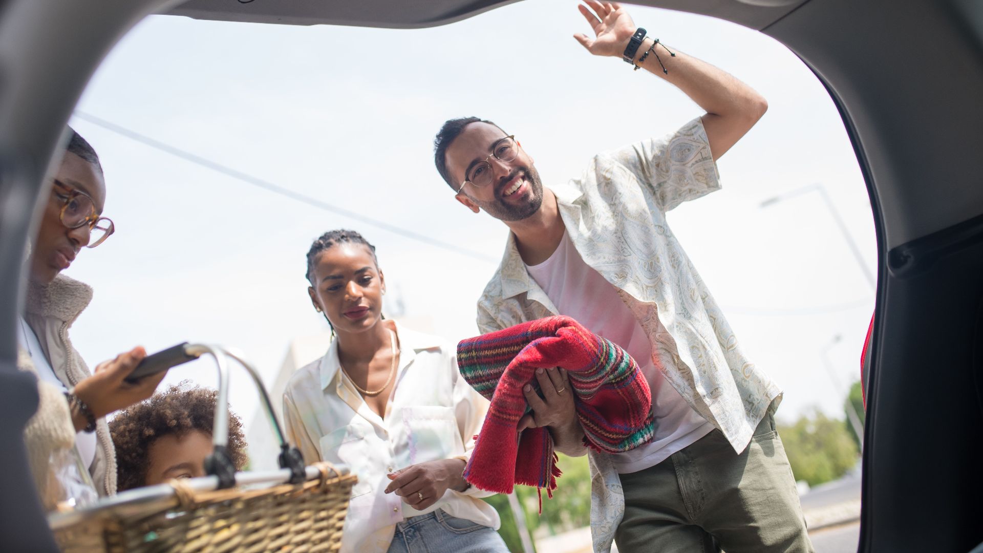 A family enjoys a picnic day outing, loading a car with love and joy on a sunny day.