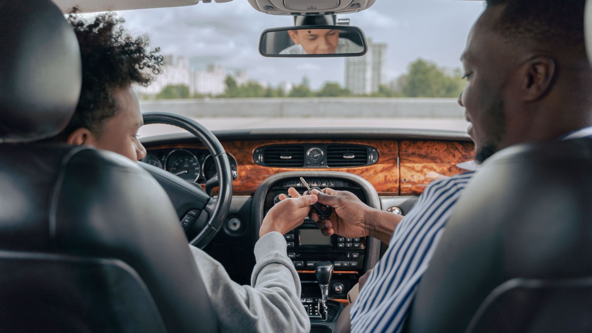 Father and teenage son inside car learning to drive, fostering bonding and guidance.