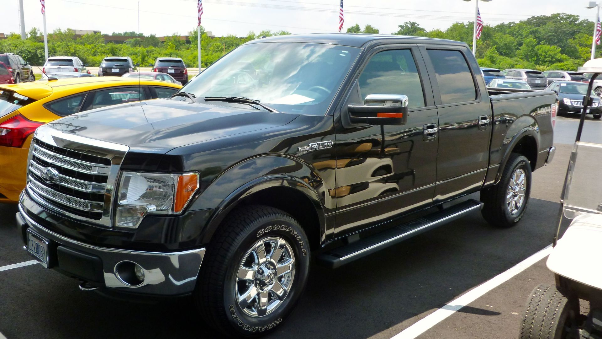 Black Ford F-150 pickup truck displayed at an outdoor dealership lot on a sunny day.