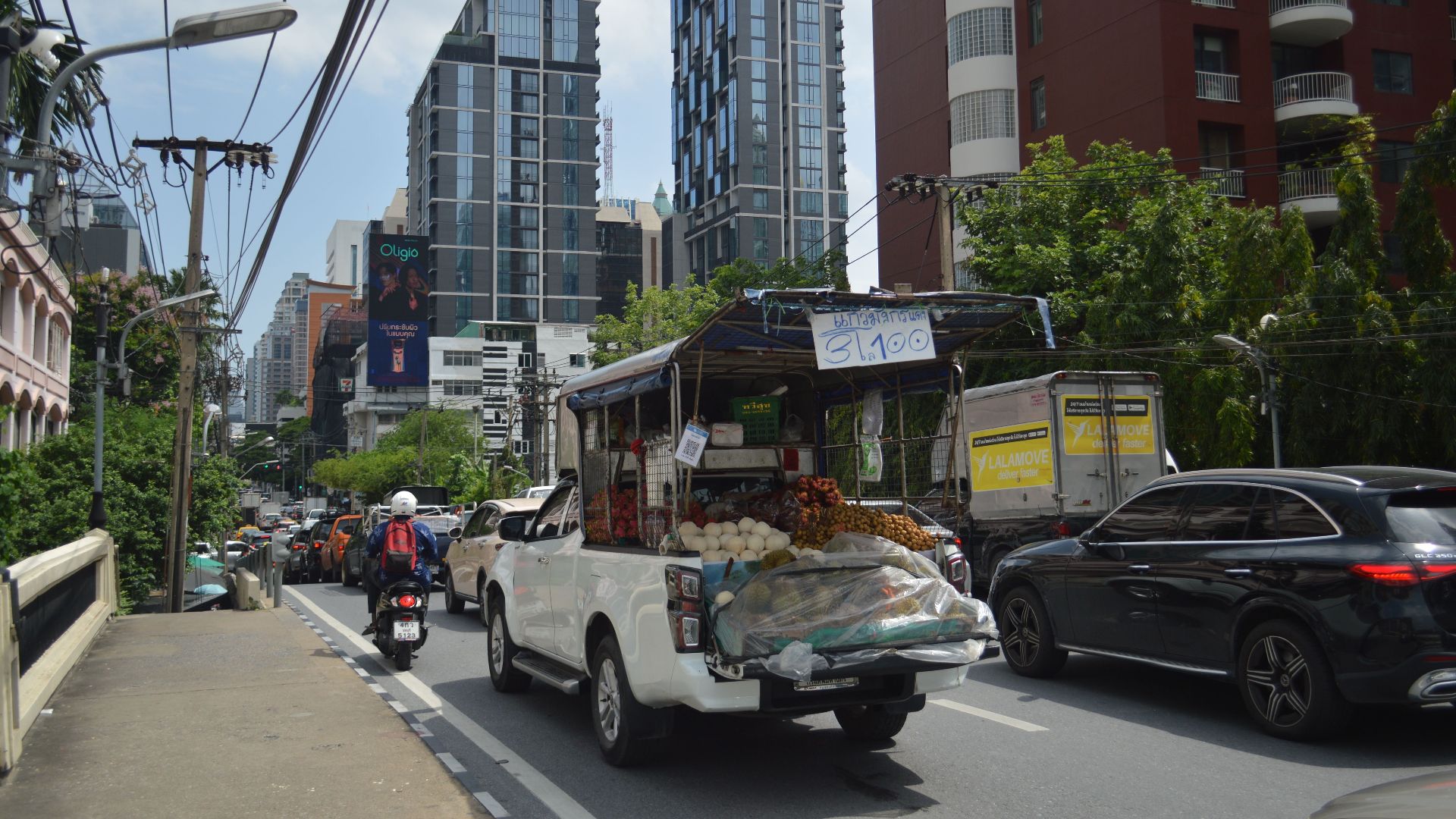 Busy street with street vendor and modern skyscrapers, vibrant urban life captured.