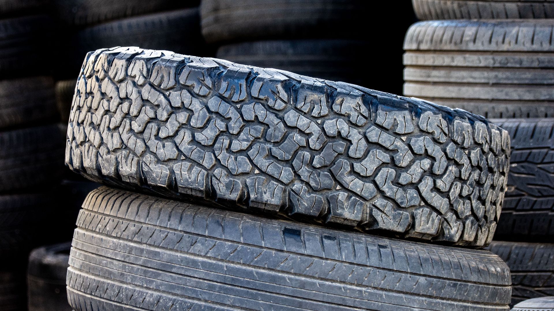 Close-up of stacked automotive tires showcasing rugged tread patterns in an outdoor setting.