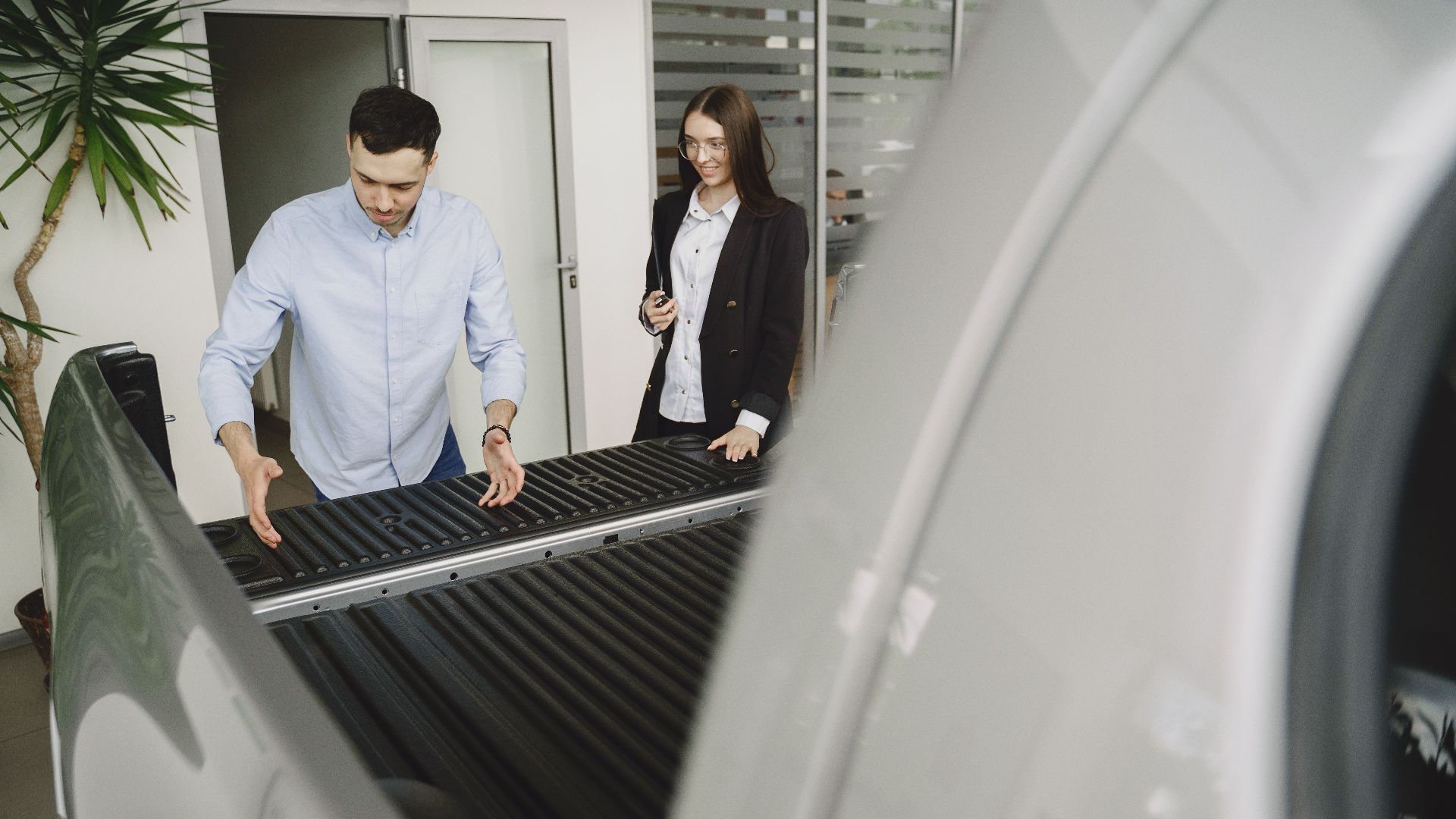 Salesman and client inspecting a pickup truck in a car dealership, discussing features.