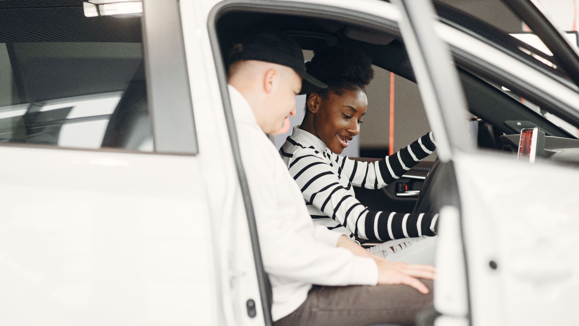 Two adults exploring a car interior at a dealership, smiling and engaged.