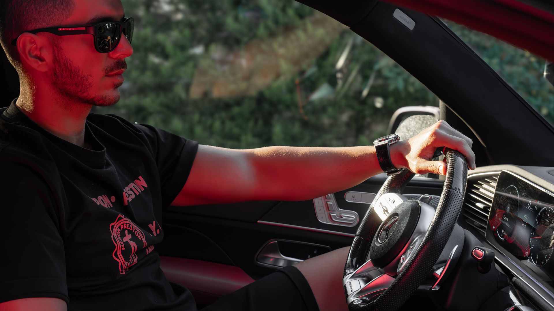 Young man in sunglasses driving a luxury car, showcasing modern automotive style.