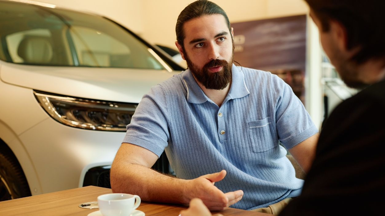 Shutterstock-2513248363, Medium shot of adult male client at desk discussing terms and conditions of purchase contract with auto dealer while buying new car at dealership center, copy space