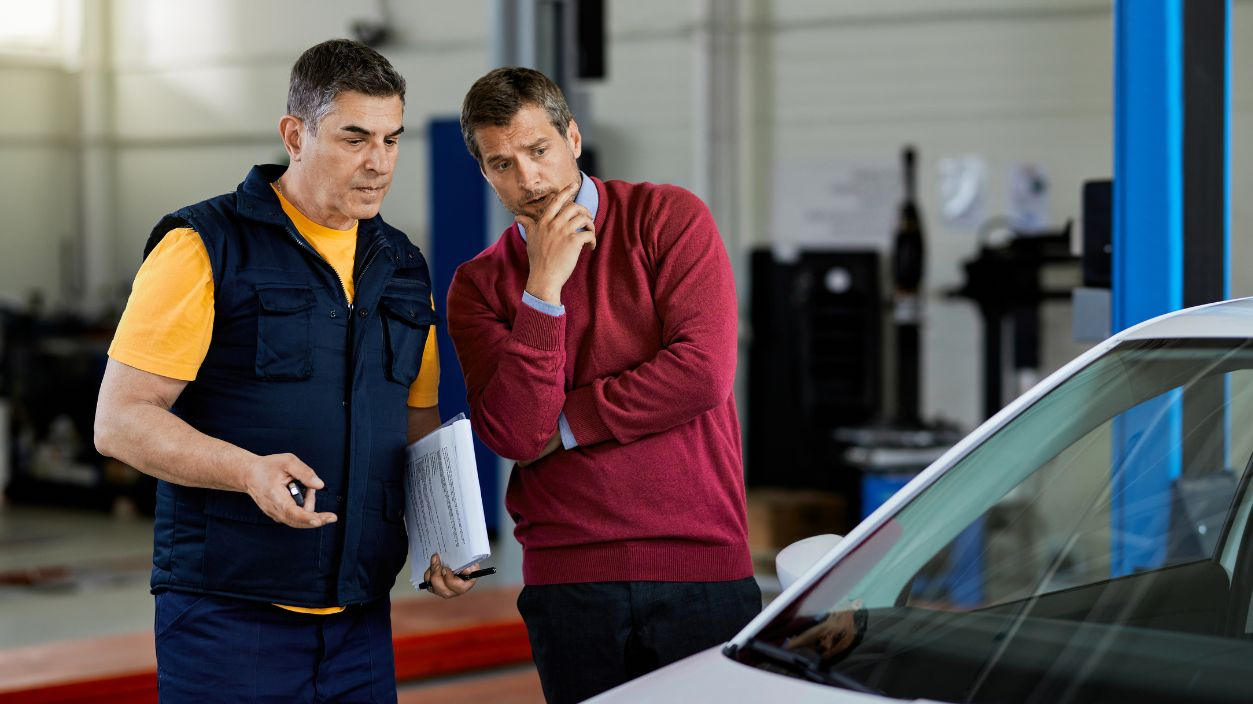 Shutterstock-1766946866, Worried customer talking with car mechanic in auto repair shop.