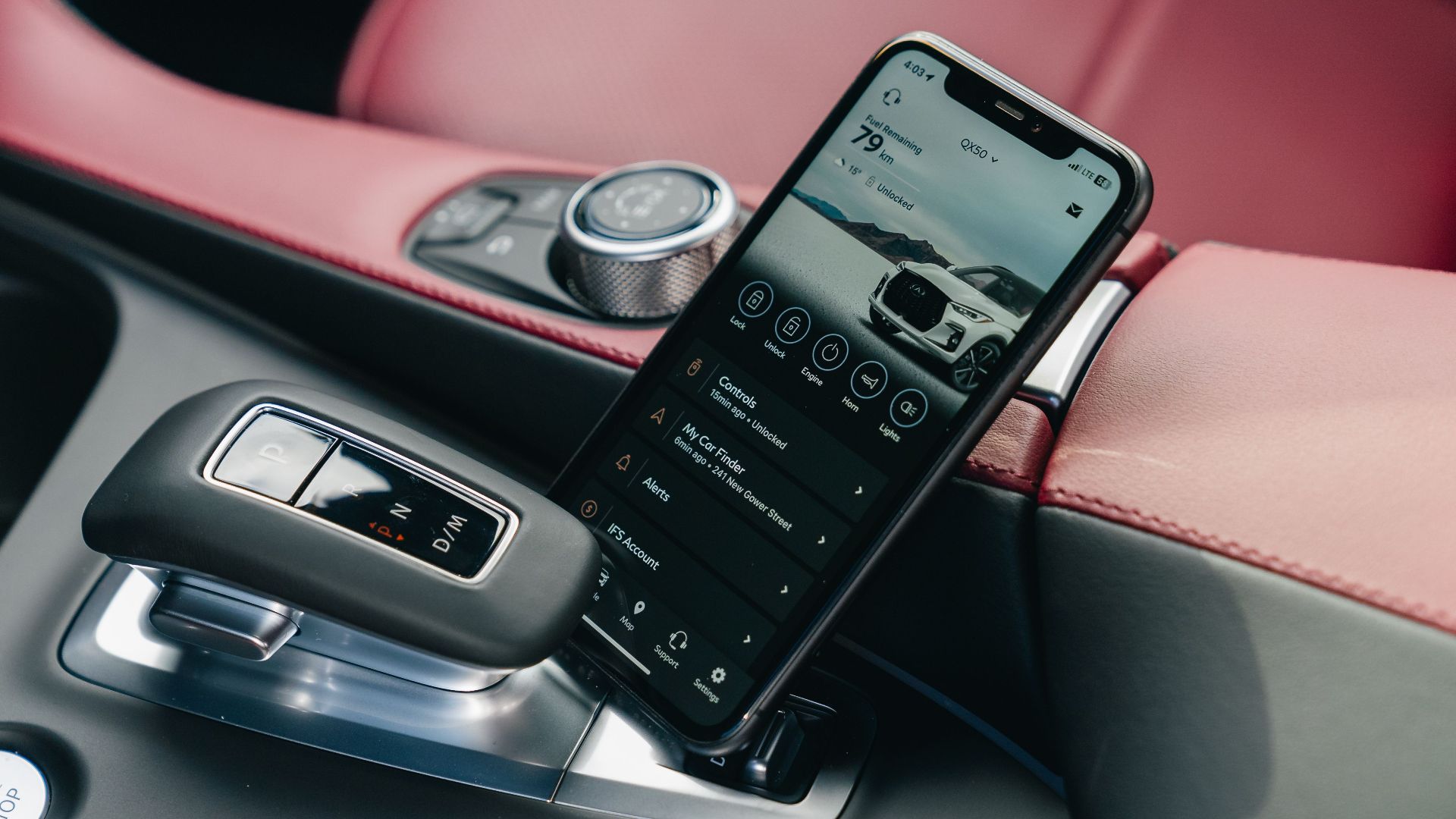 Close-up of smartphone with car control app in a luxury car's interior, showcasing modern technology.
