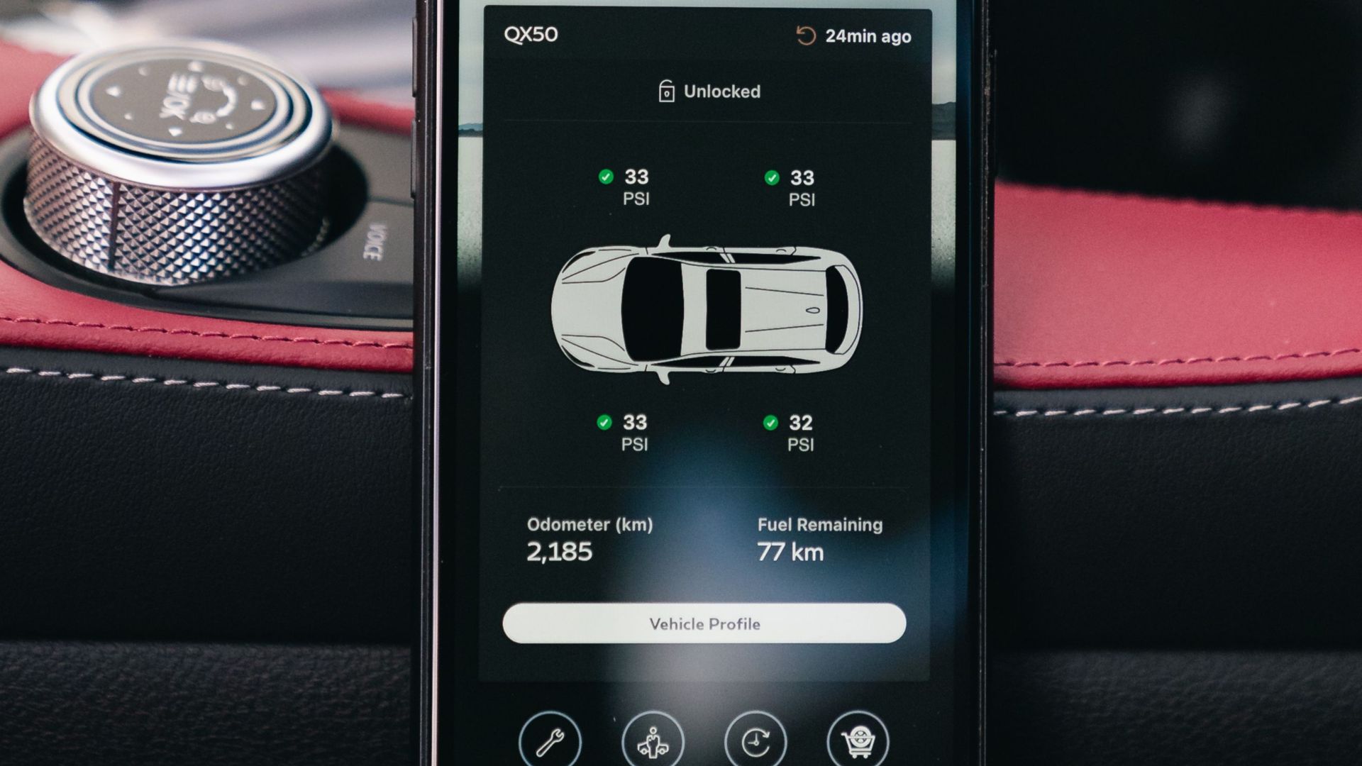 A smartphone showing a car dashboard app interface, placed inside a vehicle.