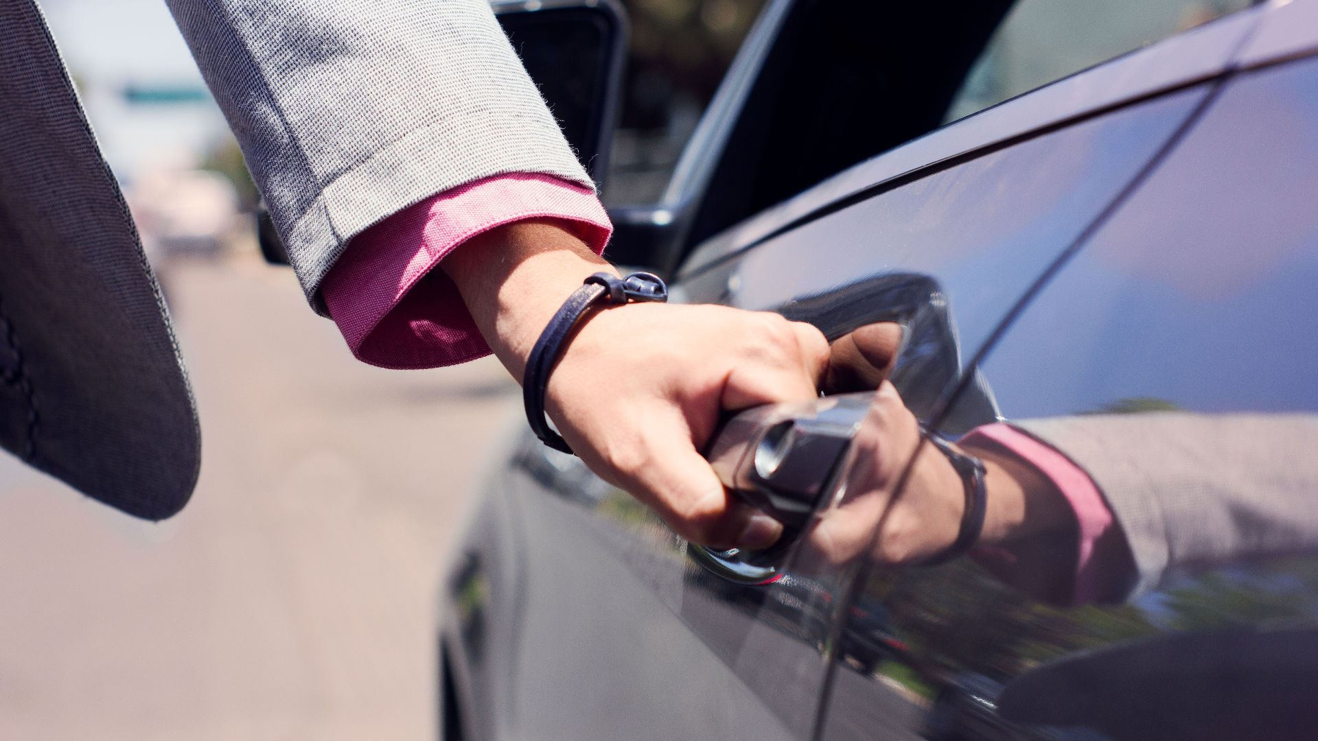 Close-up image of a hand opening a car door, highlighting business and transit themes.