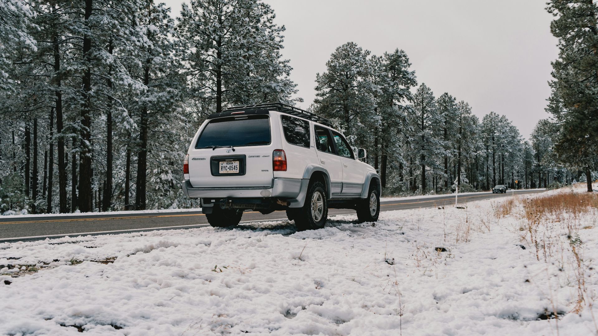 A white van driving down a snow covered road