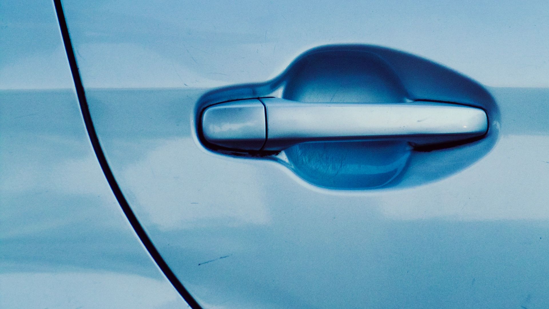 Close-up of a car door handle with blue tint. Modern automotive detail.