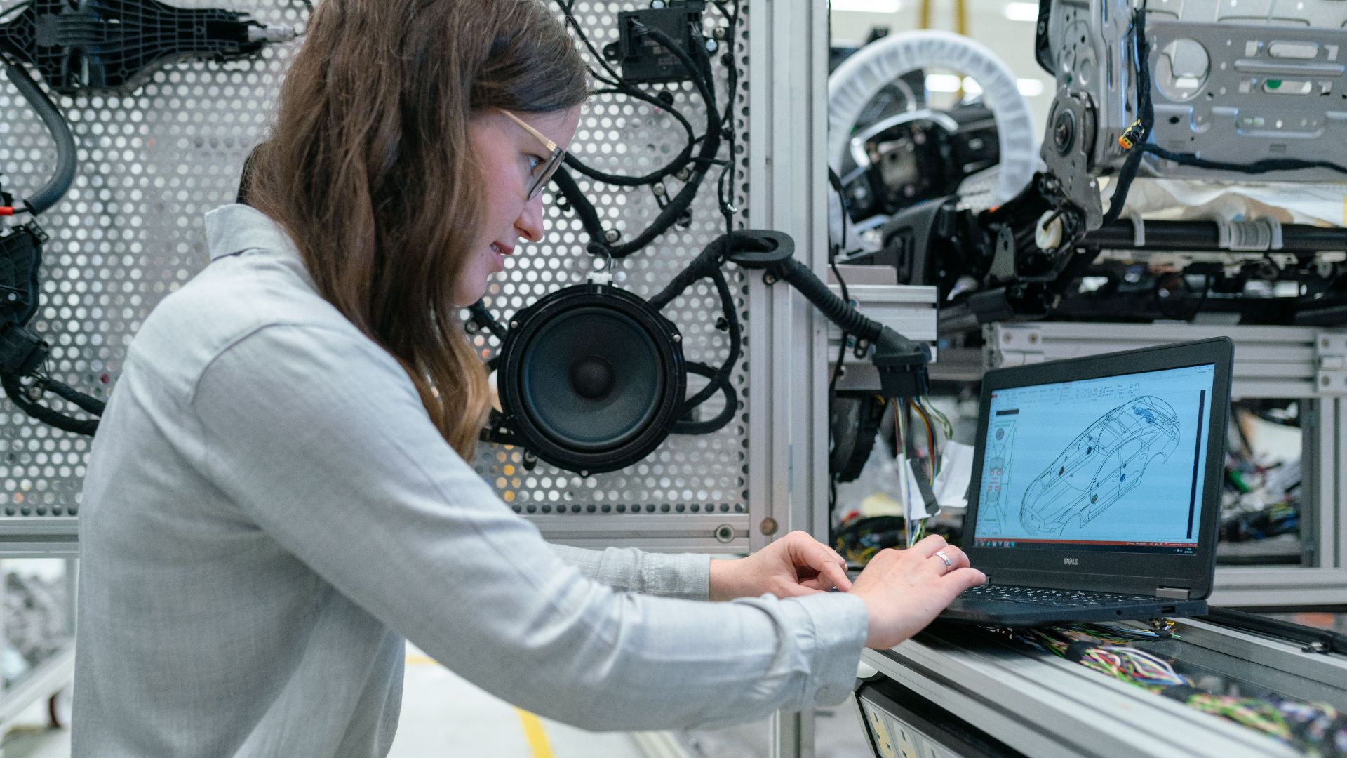 Woman conducting engineering research in a sound system workshop using a laptop.