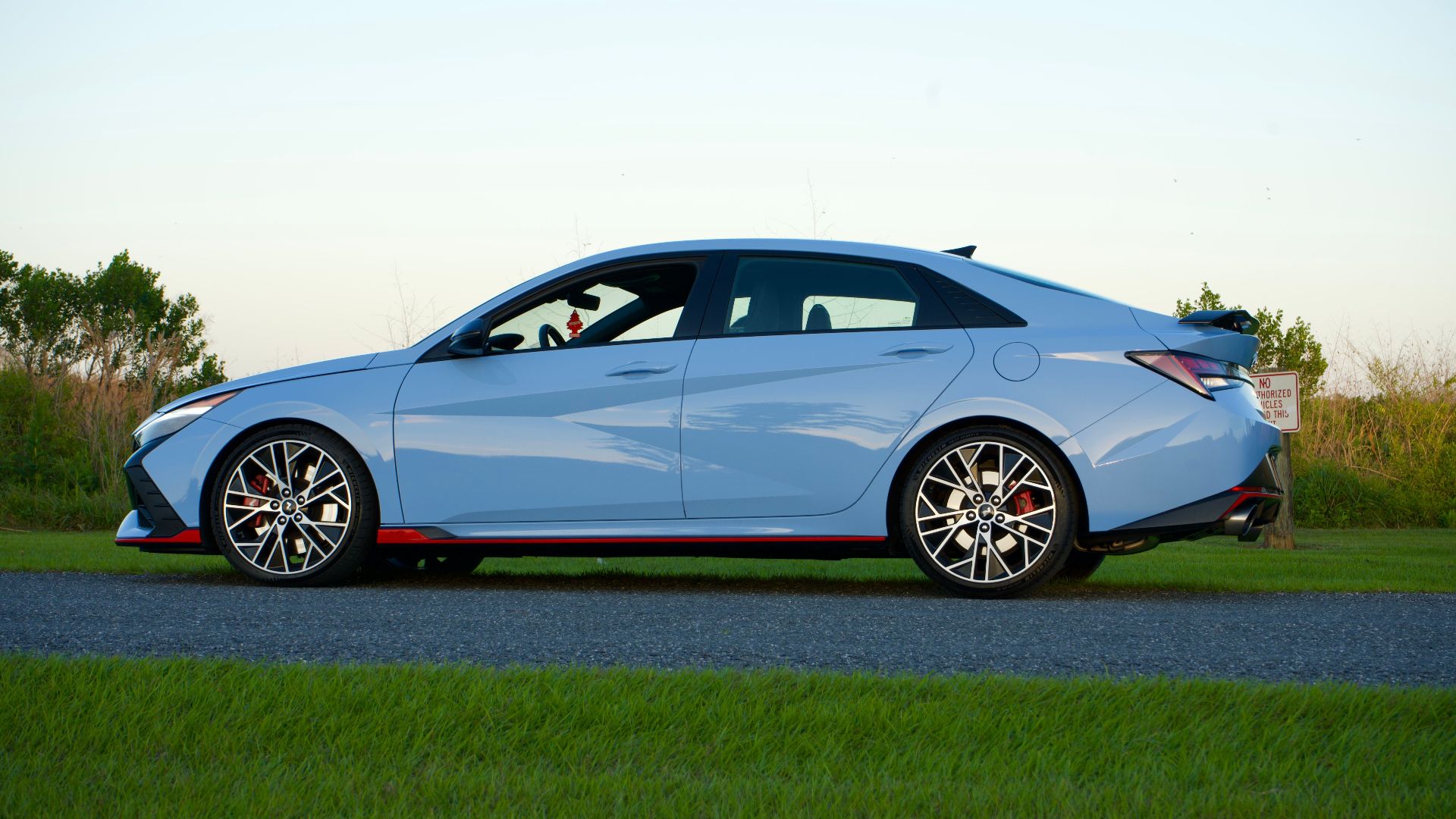 Side view of a blue Hyundai Elantra N parked on a road with grassy surroundings in Kissimmee, FL.