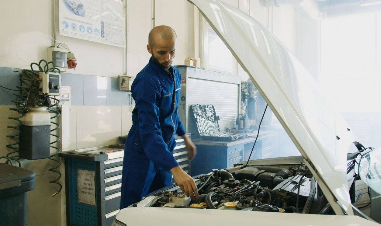 Mechanic in blue uniform inspecting a car engine