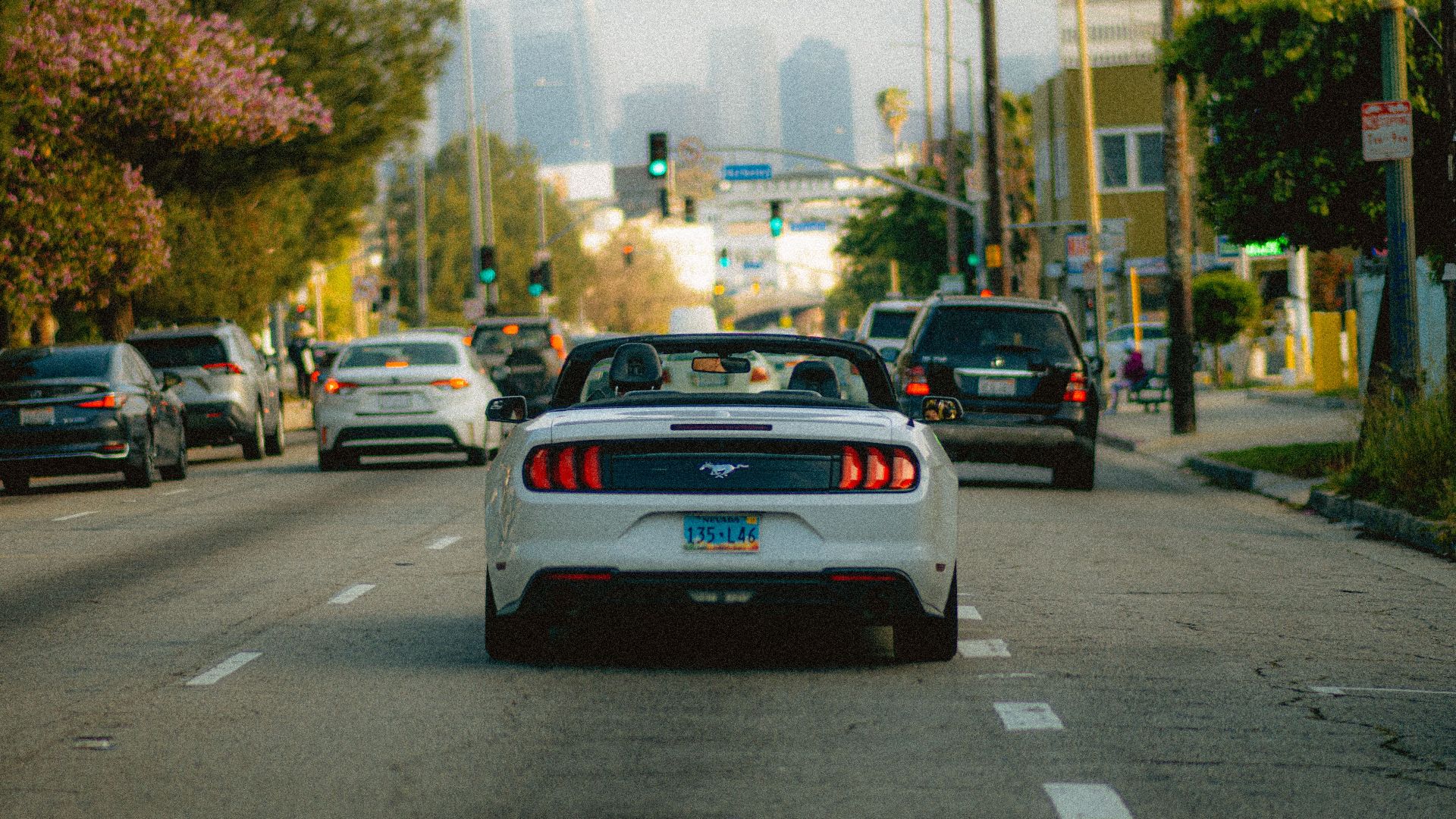 White convertible car on a busy Los Angeles street with a city skyline in the background.