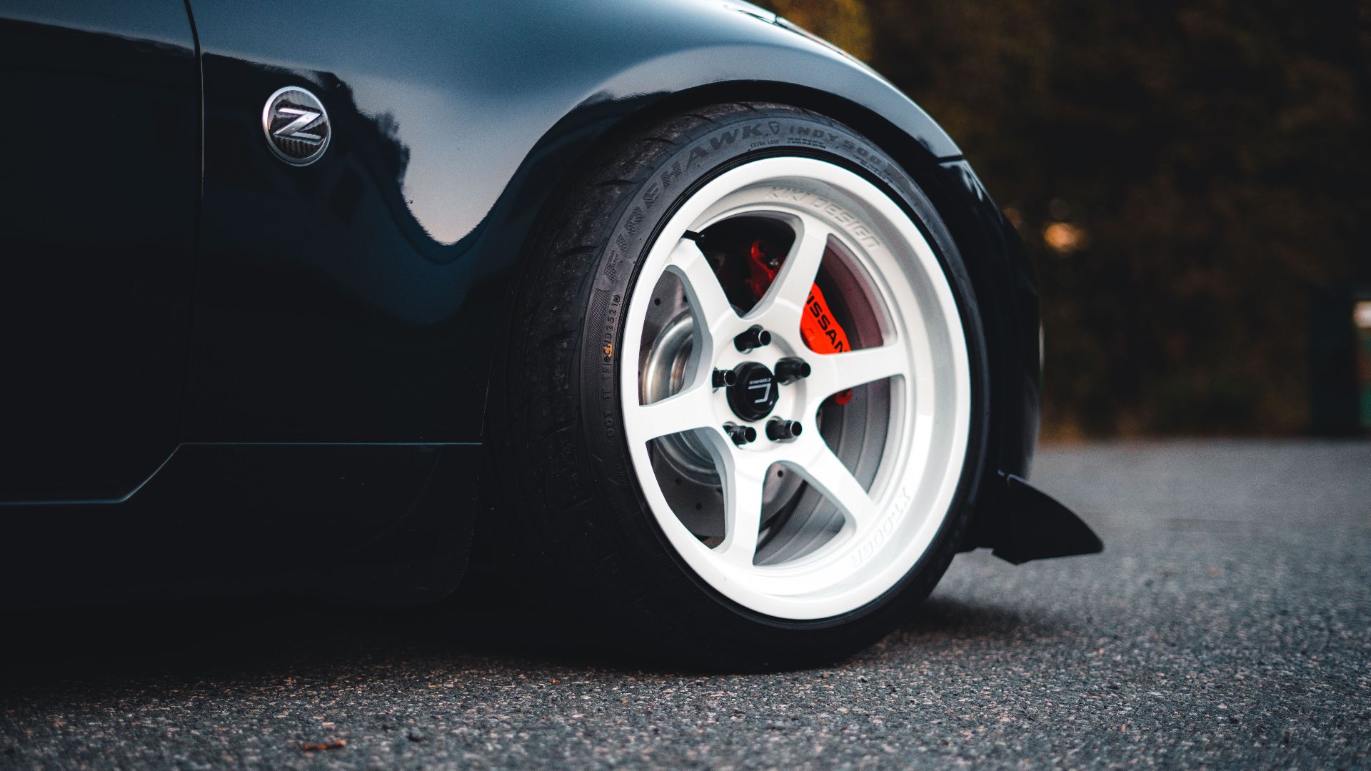 A detailed view of the wheel and rim on a sleek black sports car parked on asphalt.