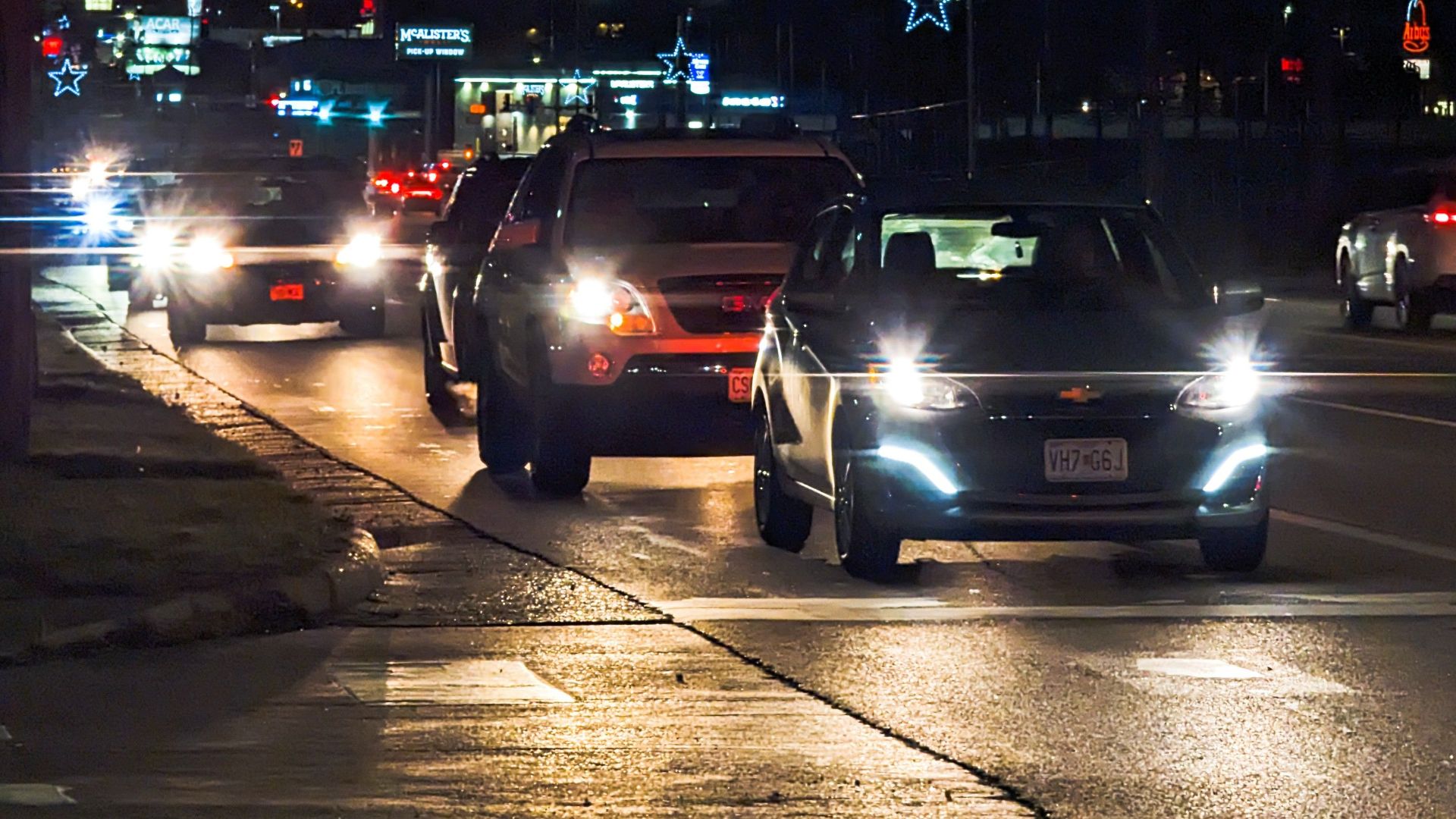 Busy urban street at night showcasing car traffic and illuminated star decorations.