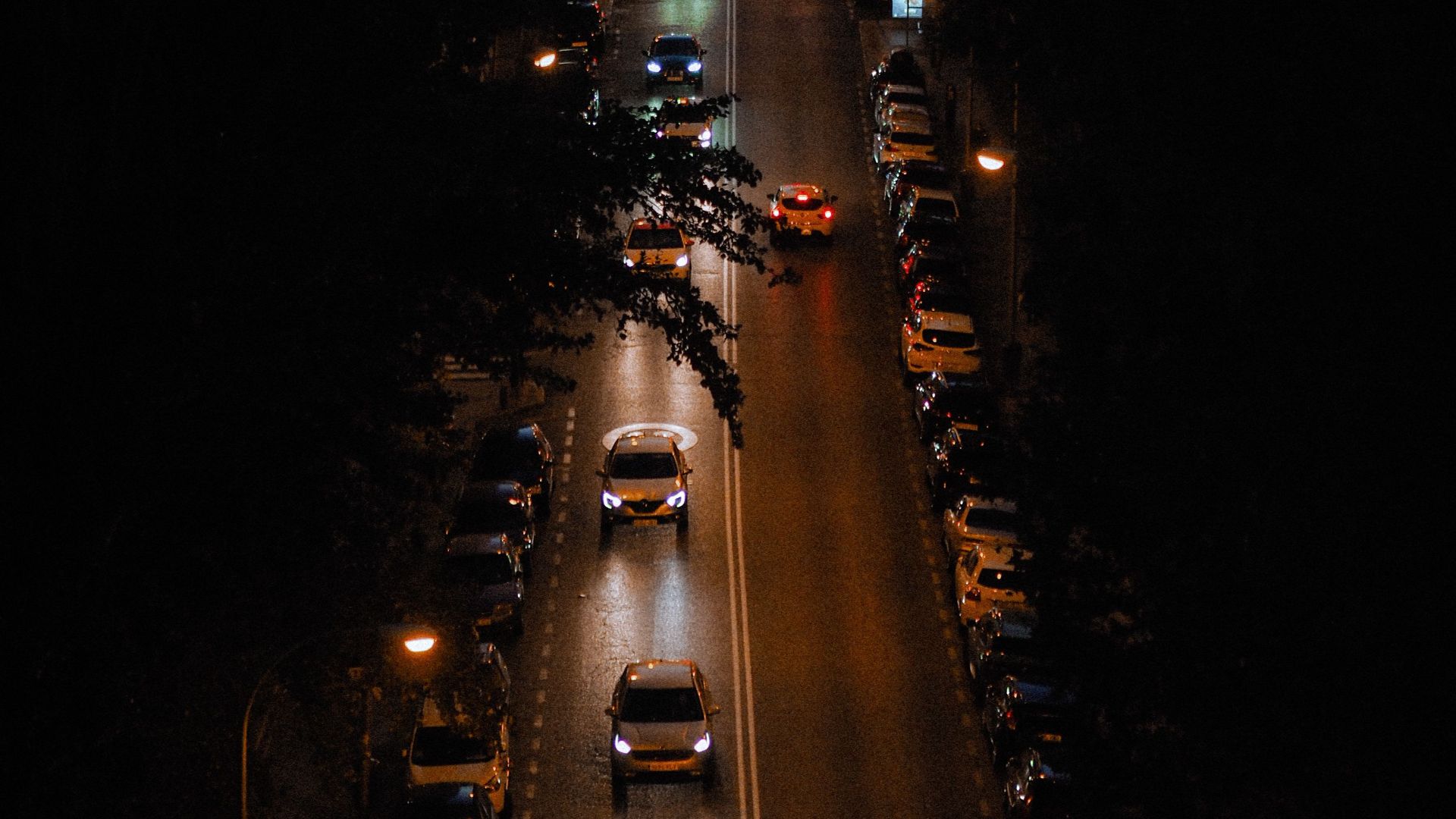 Aerial photograph of a city street illuminated by car lights during nighttime, showcasing urban nightlife.