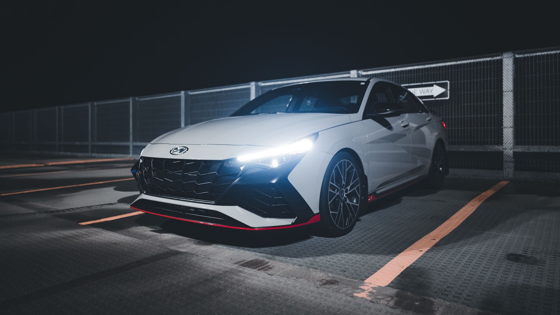 A white sports car with glowing headlights parked at night, showcasing modern design and elegance.