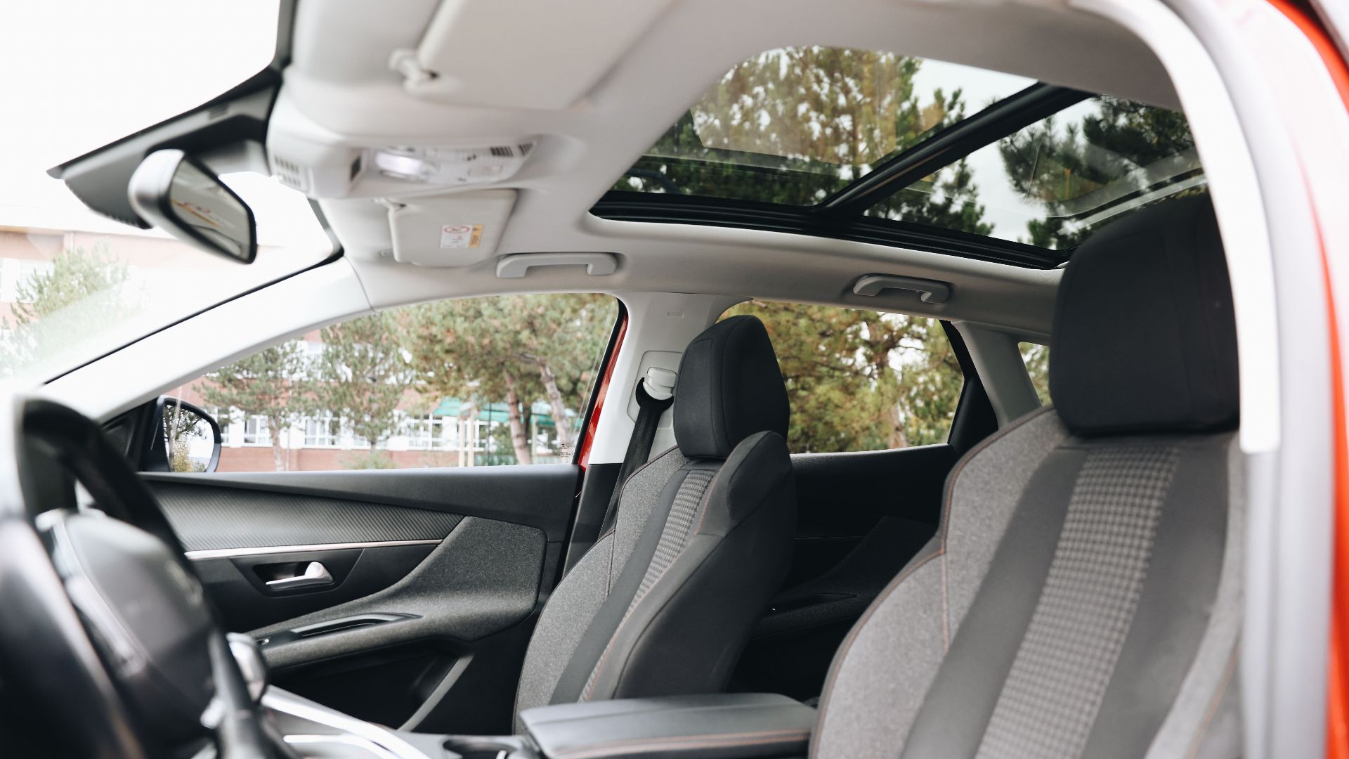 Spacious modern car interior featuring a panoramic sunroof and front seats.