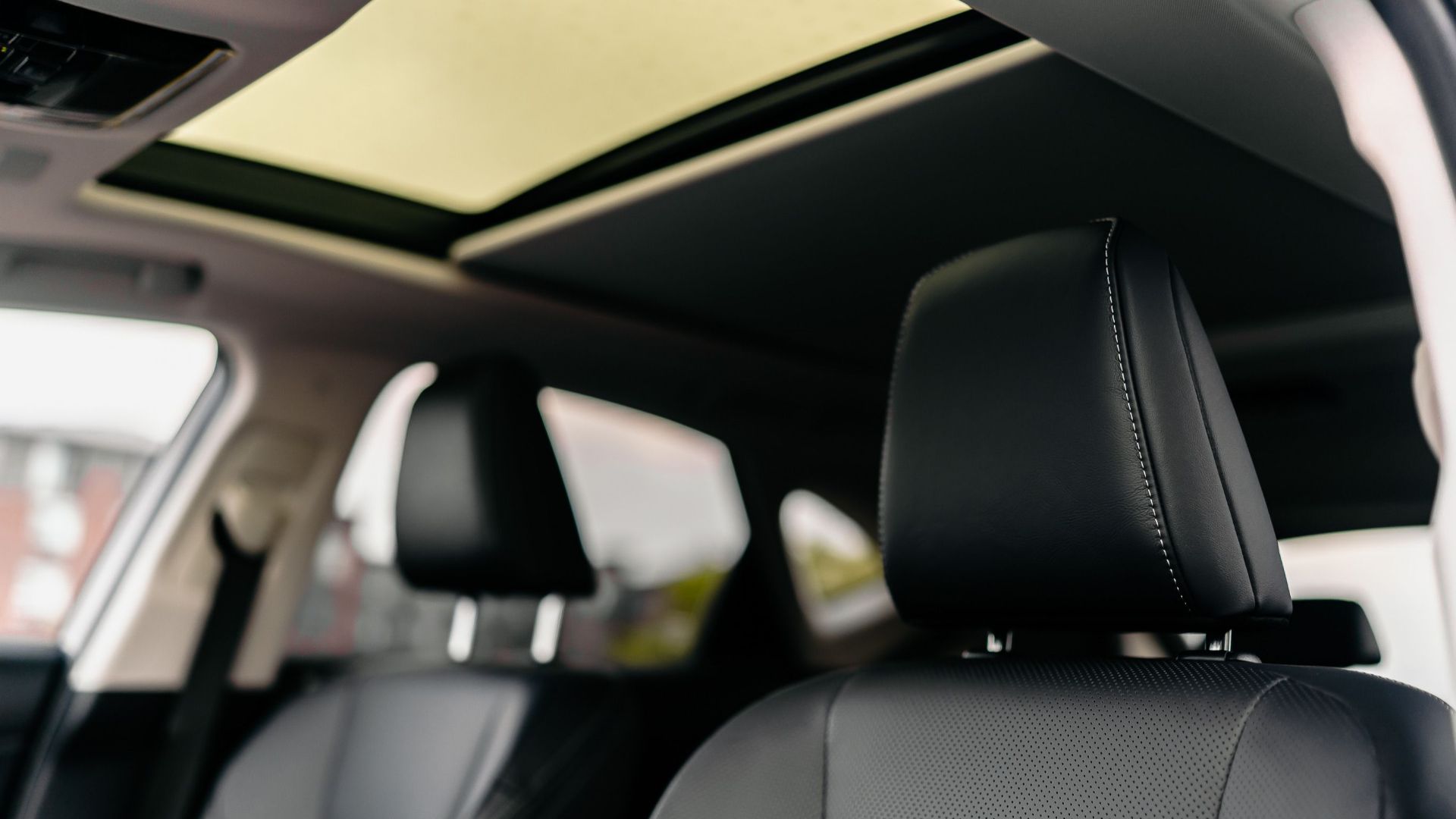 Explore the modern luxury of a car interior featuring leather seats and a sunroof.